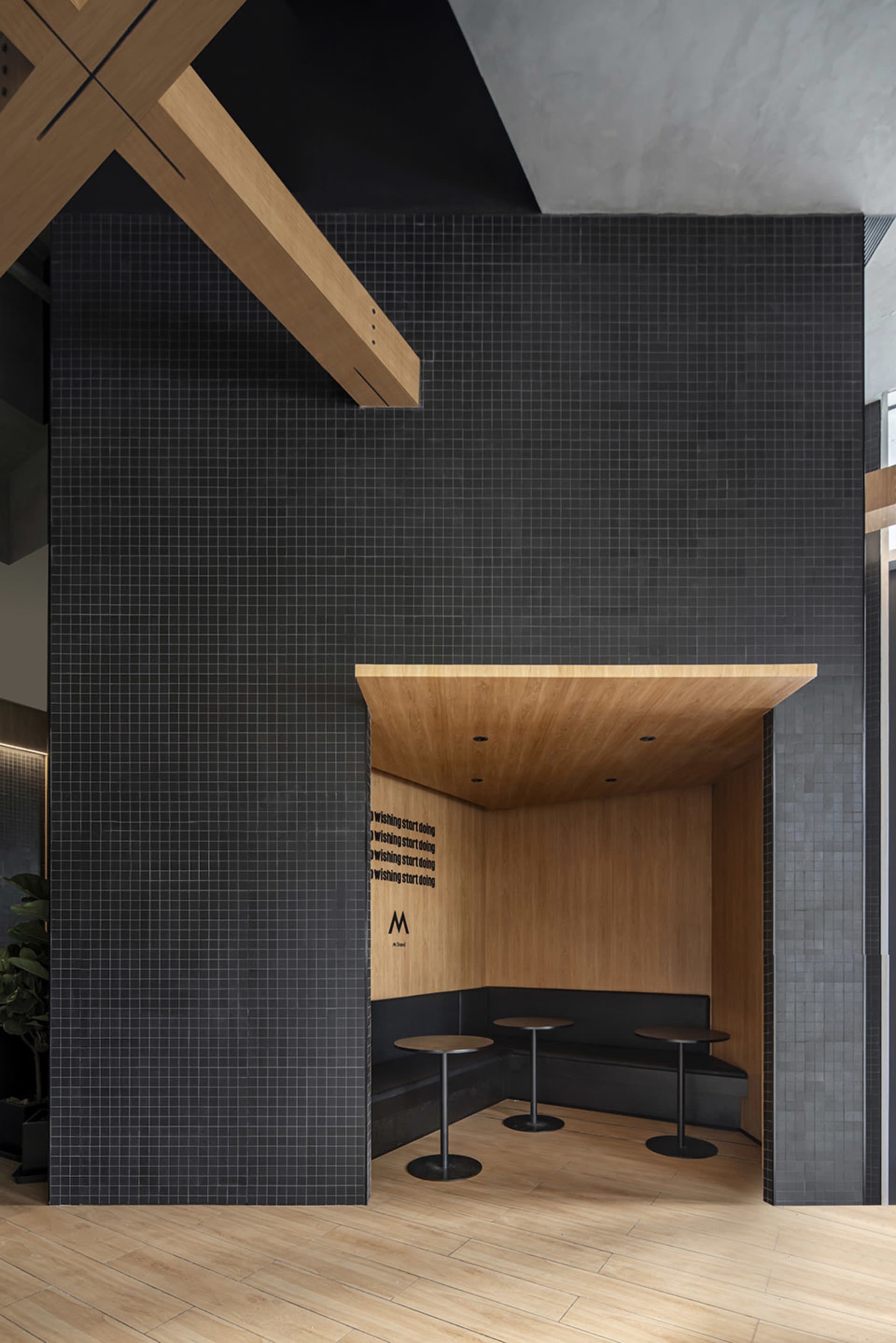 Modern restaurant dining area with black tile walls, multiple tables, and chairs, creating a sophisticated and inviting atmosphere