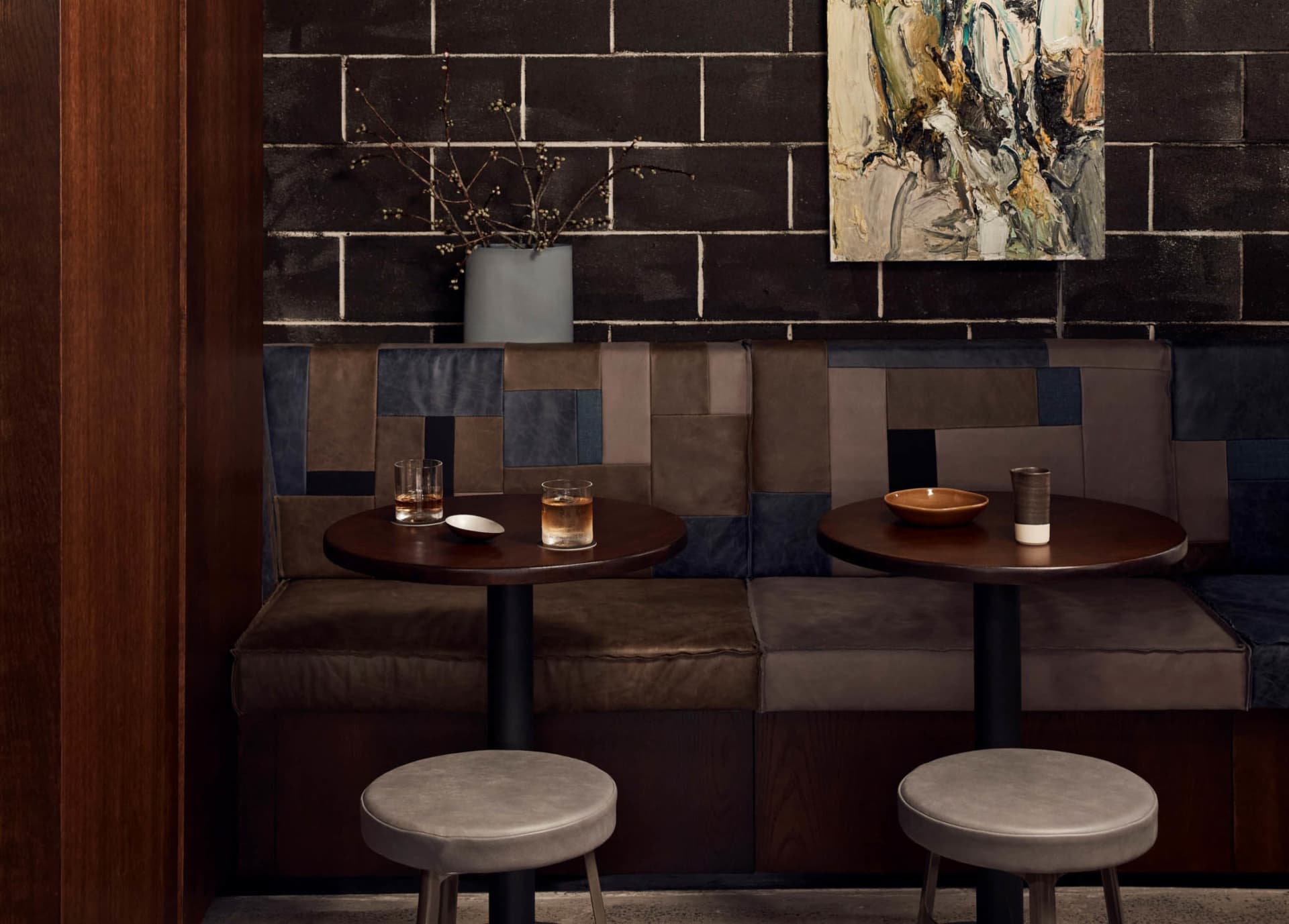 Two dining tables with vases and chairs in a restaurant setting, accompanied by a potted plant, creating a welcoming atmosphere