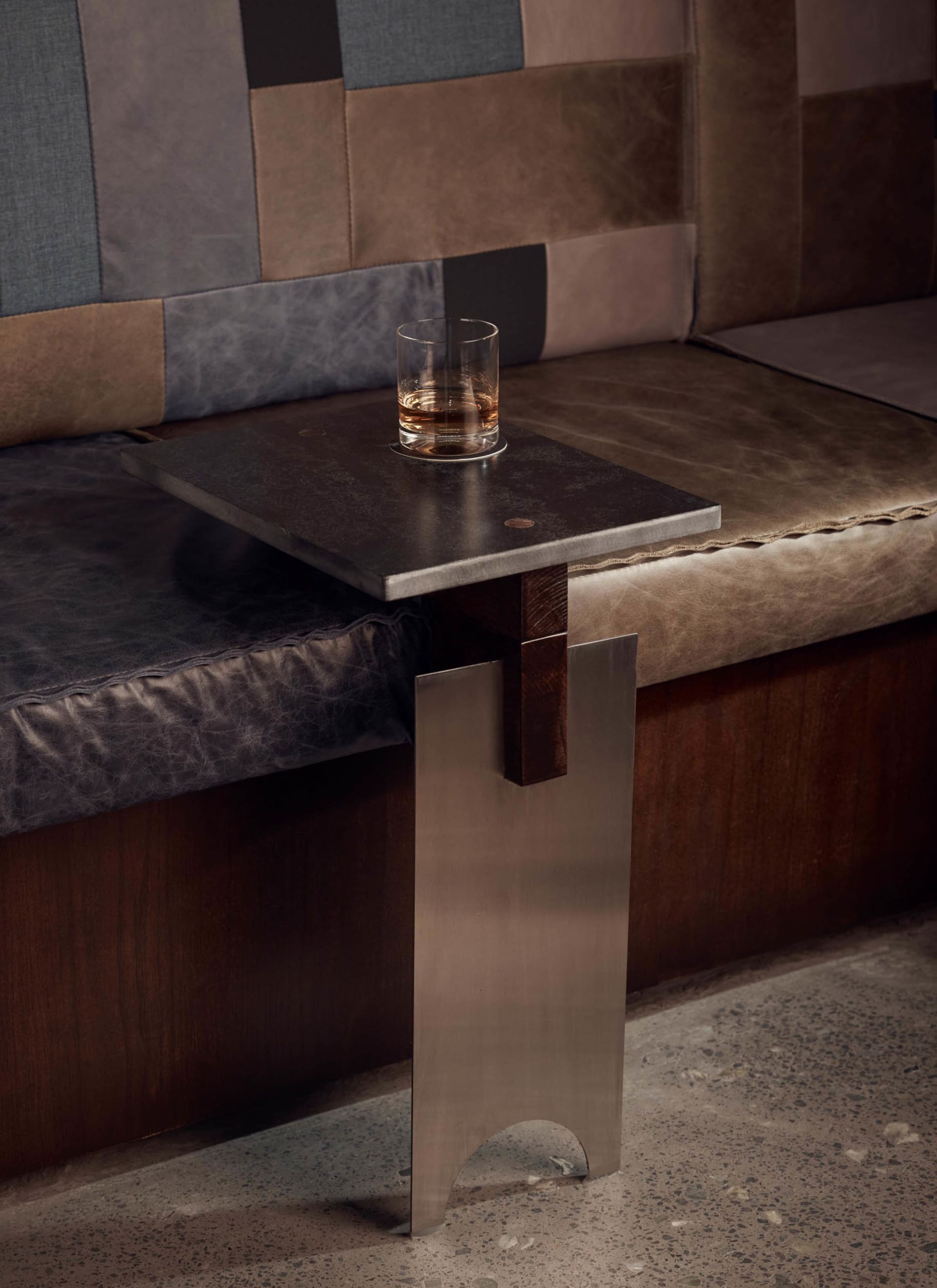 A cozy living space with a large couch, a smaller bench, and a glass of whiskey on a small table, creating a relaxed and sophisticated atmosphere