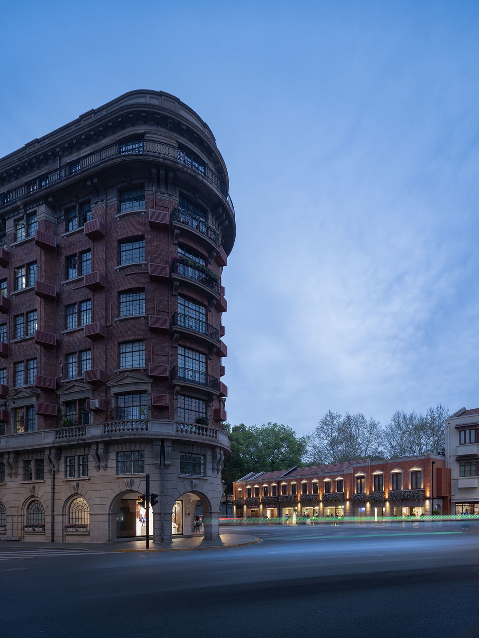 A traditional city building with red brick walls and multiple floors, featuring large windows that allow natural light to enter the interior spaces
