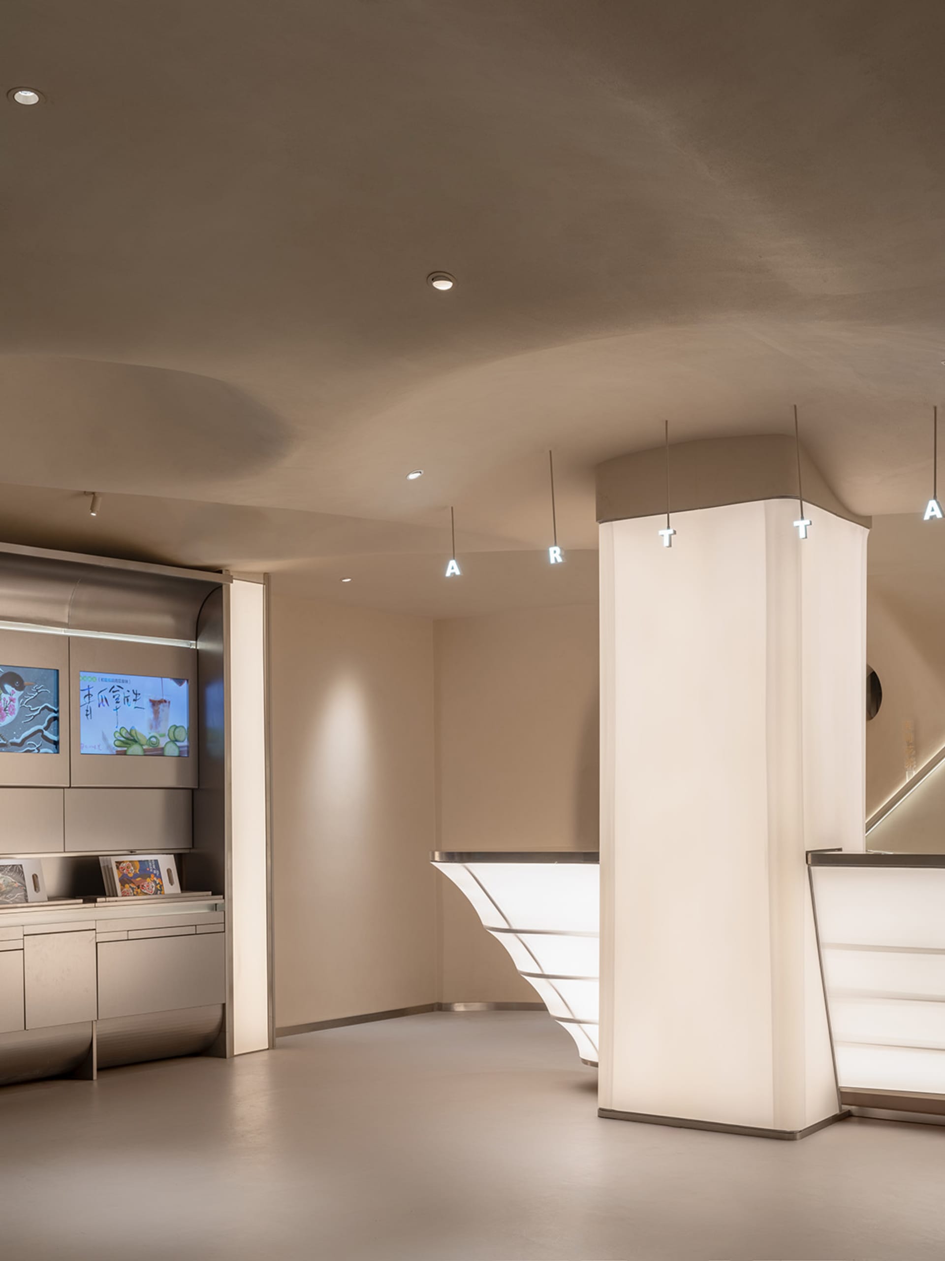 Modern lobby with white walls, TV screens, and clocks, featuring various artworks and a contemporary atmosphere