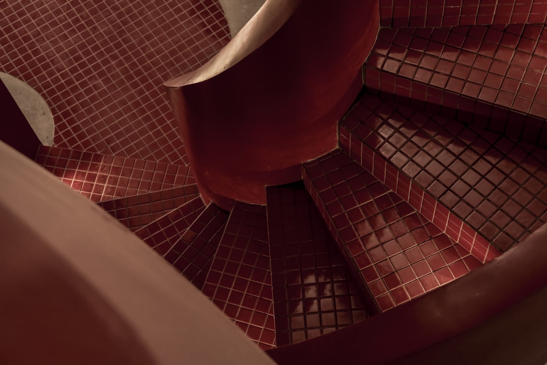 A well-lit staircase with red brick walls, wooden steps, and a metal railing, creating a warm and cozy atmosphere