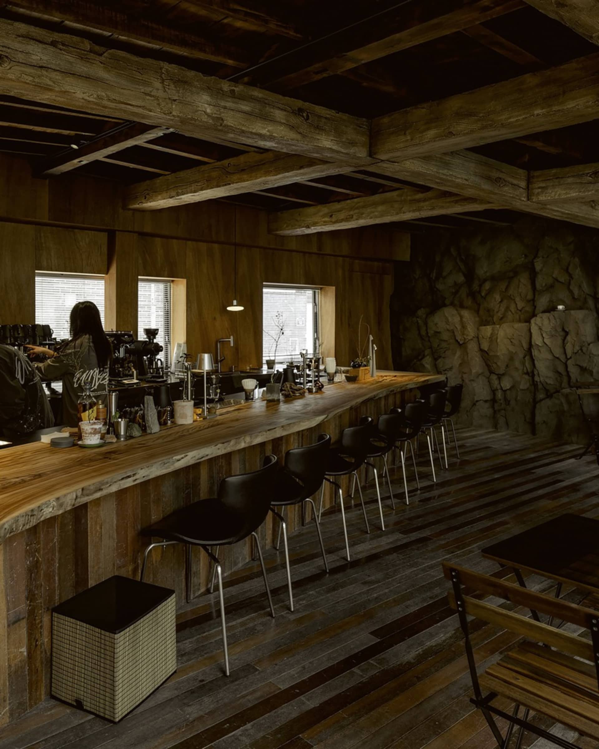 Modern bar area with a wooden countertop, stools, and chairs, creating a warm and inviting atmosphere