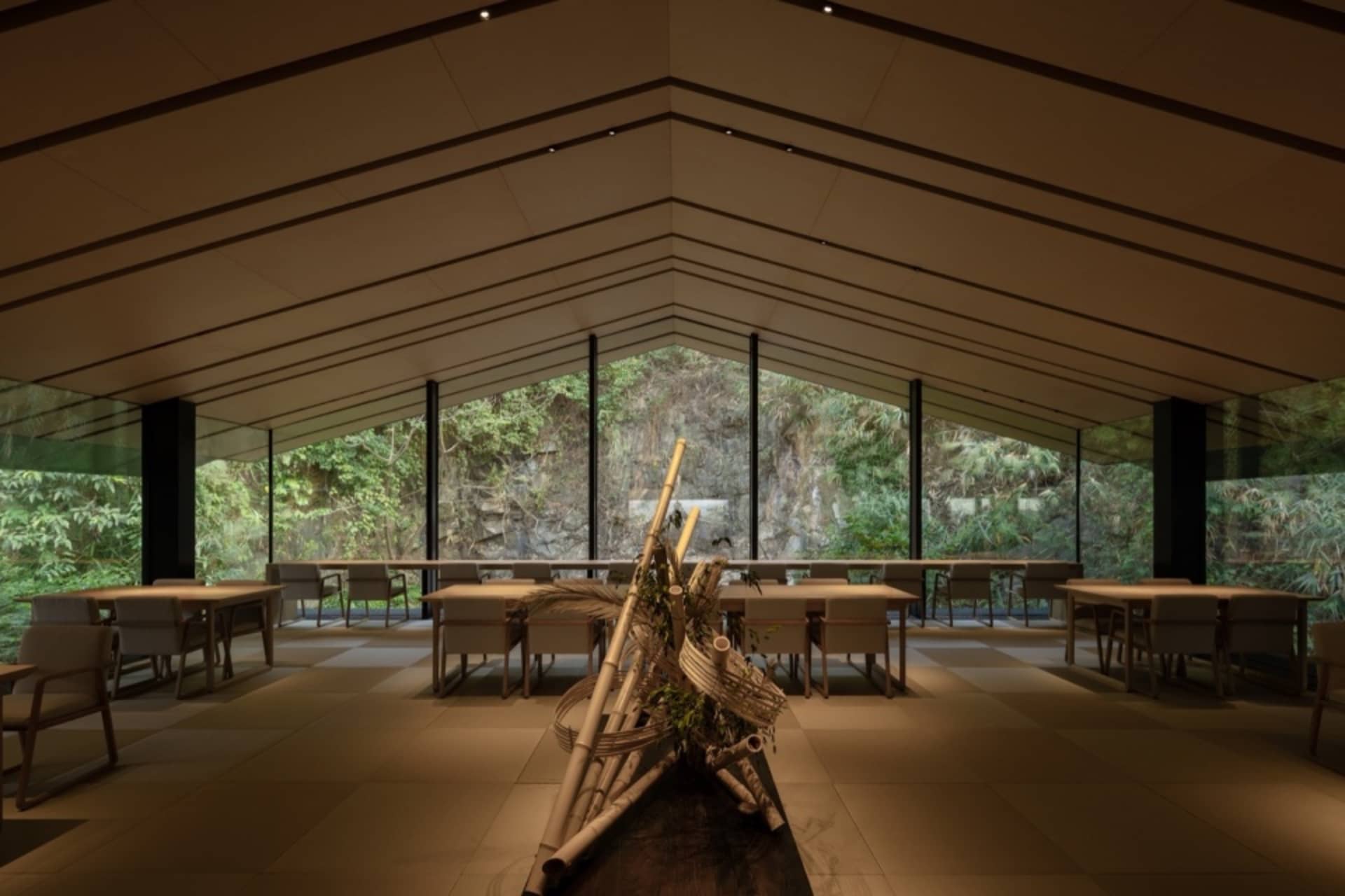 Open modern restaurant interior with tables, chairs, potted plants, and artwork on the walls