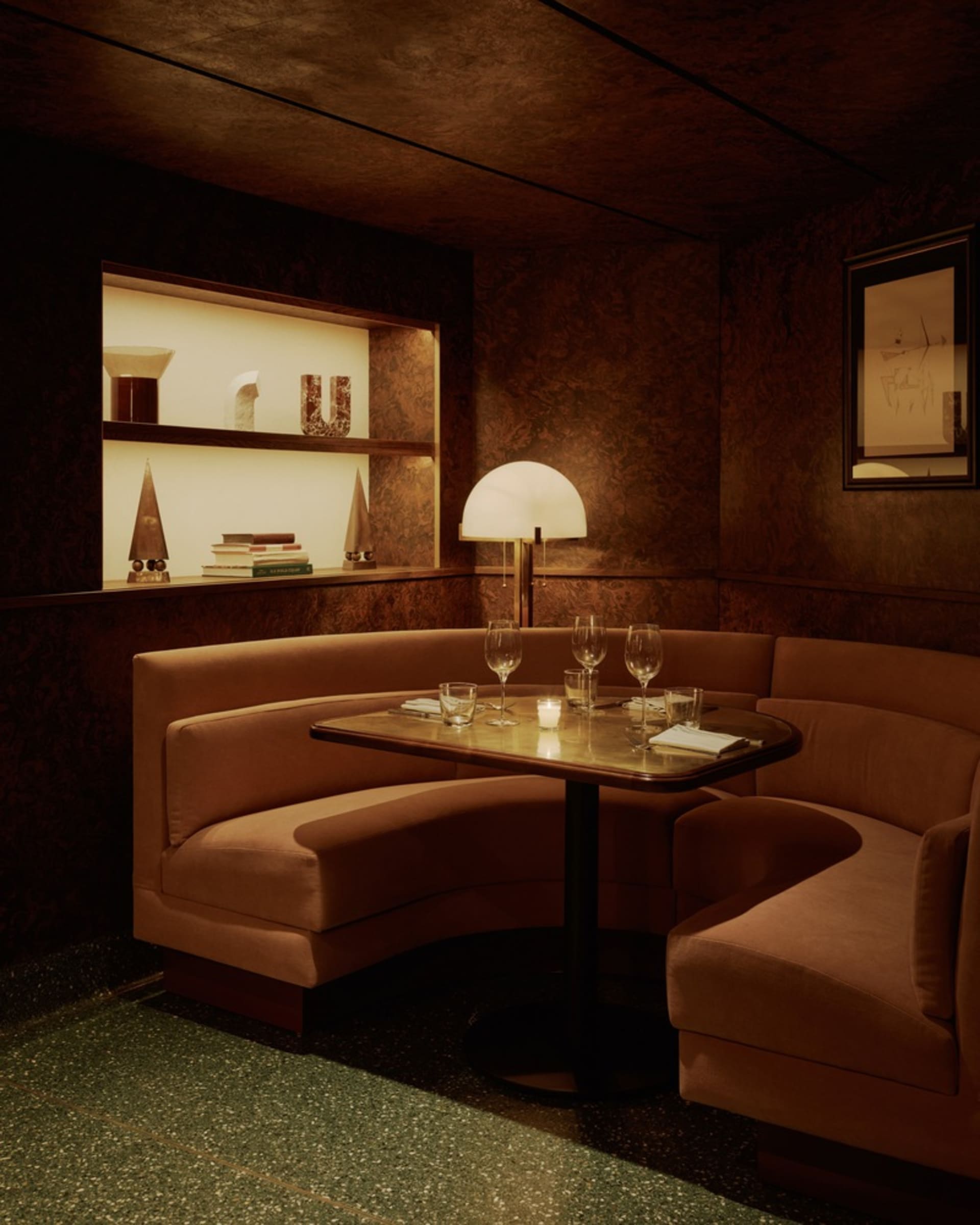 Dimly lit living space with two couches, a dining table, and wine glasses, adorned with books on the walls
