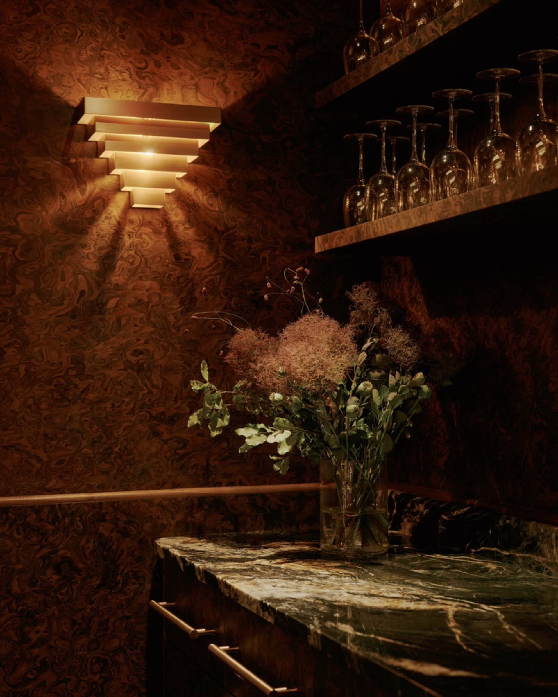 Elegant dining space with a marble countertop, brown and gold color scheme, and wine glasses