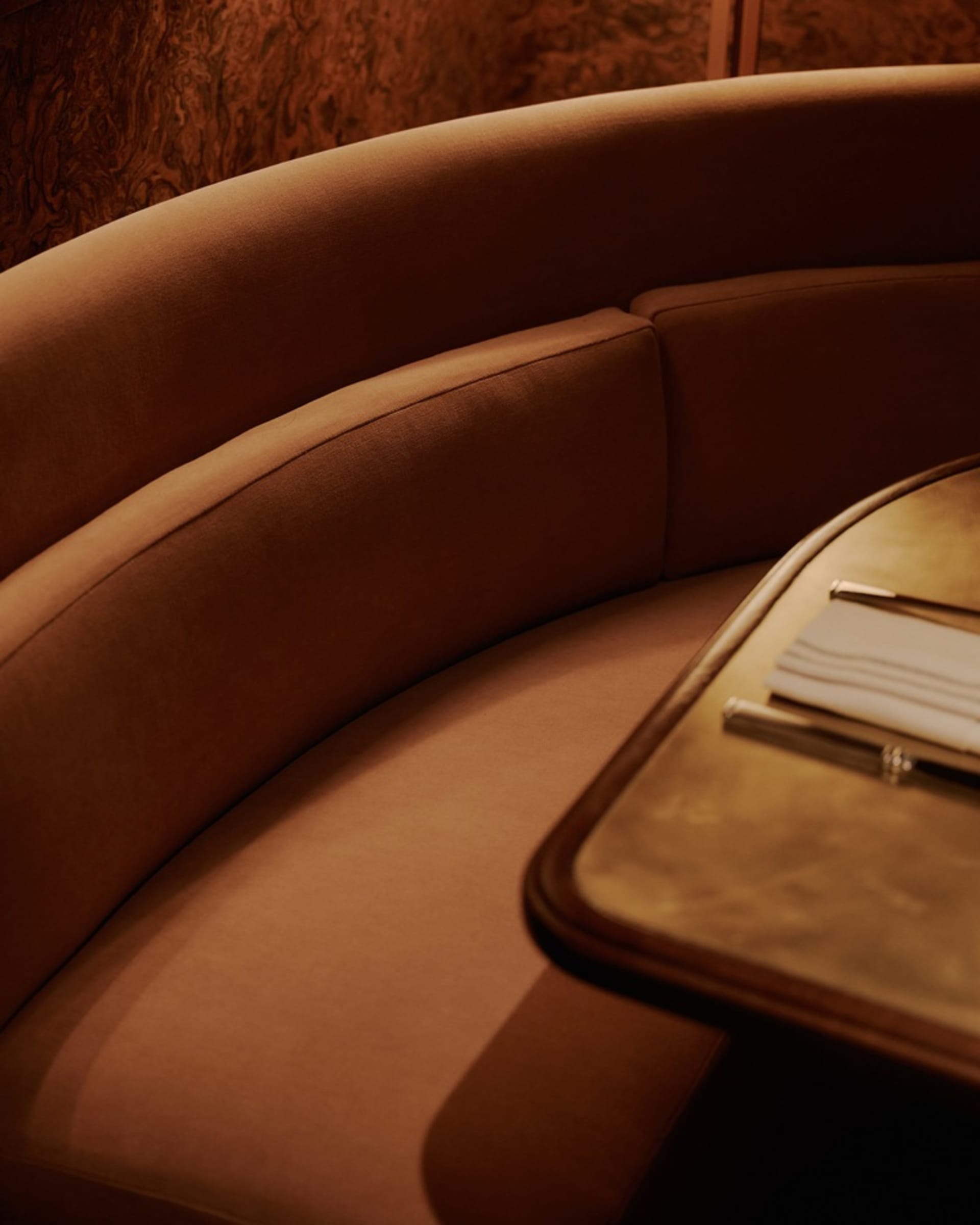 A brown leather couch and wooden dining table create a cozy seating area with two chairs and a wine glass, suggesting a space for relaxation and socializing