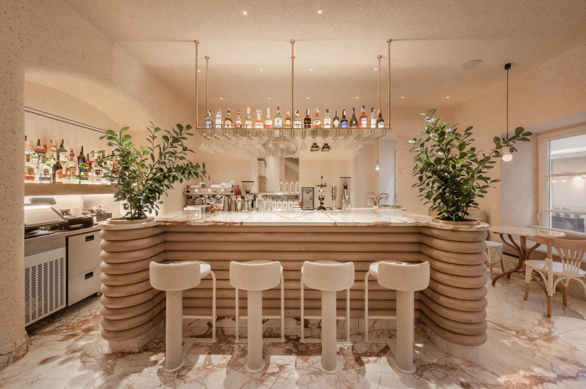 A modern bar area with a long counter, stools, and bottles, featuring a combination of white and brown elements