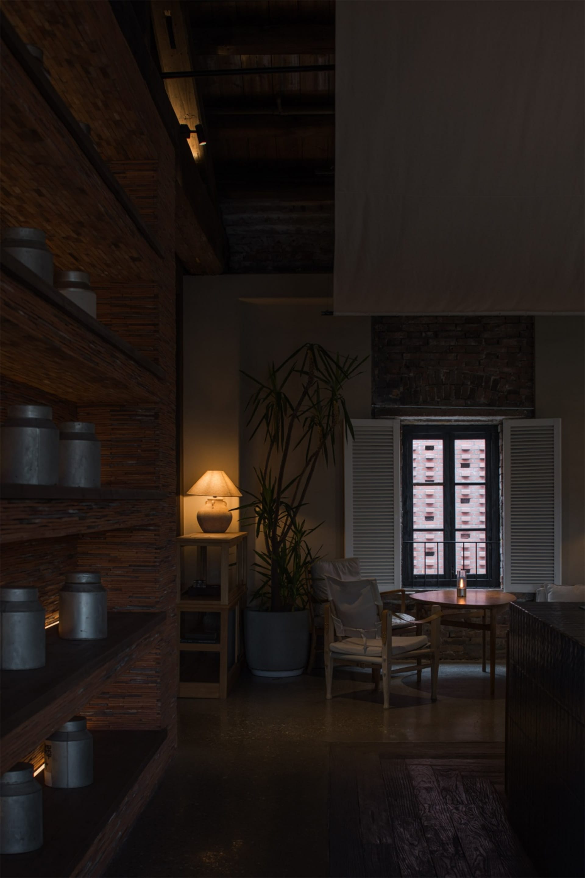 A well-lit living space with a dining table, chairs, potted plants, and vases on a wooden floor