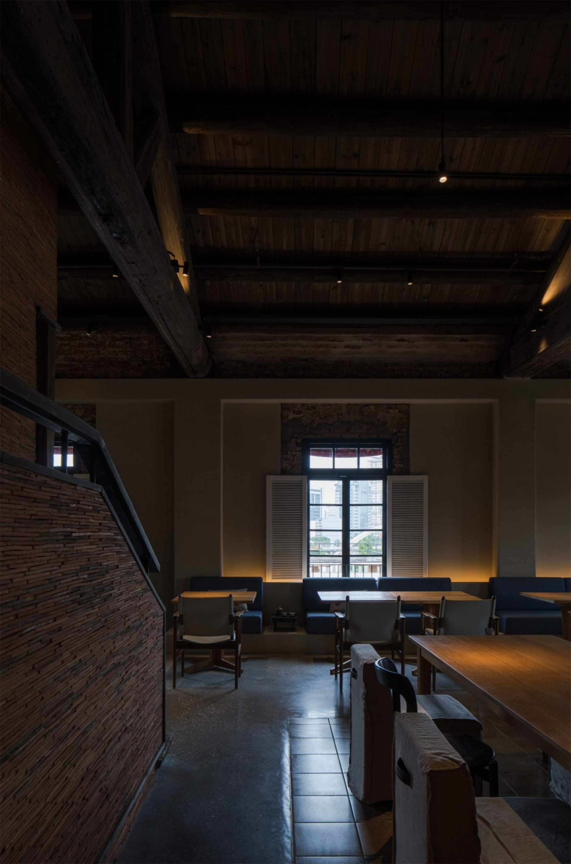 Warm and inviting restaurant interior with wooden floors, brick walls, and high ceilings, featuring multiple tables and chairs
