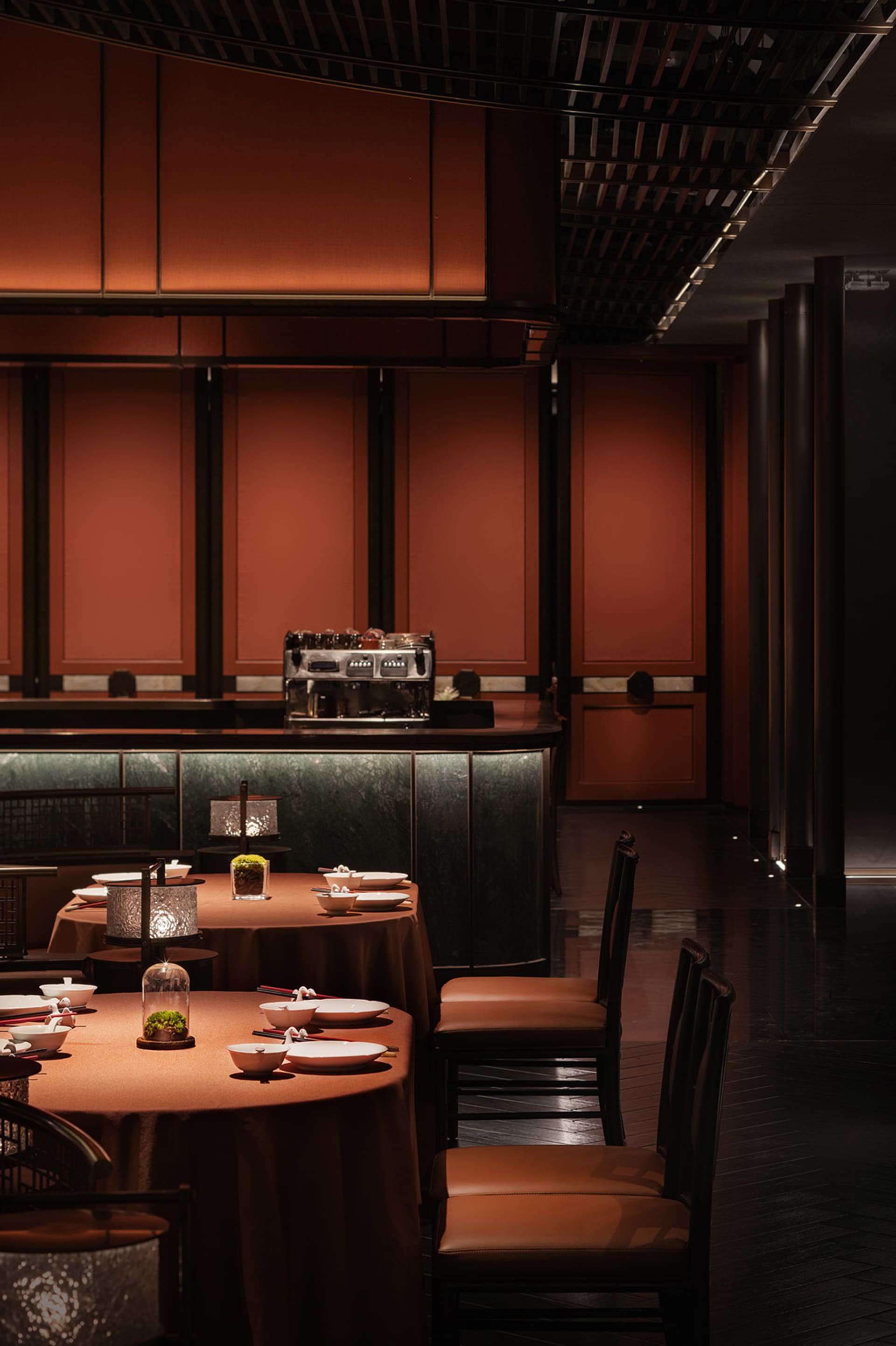 Elegant dining area with tables, chairs, and decorative vases, surrounded by red-painted walls