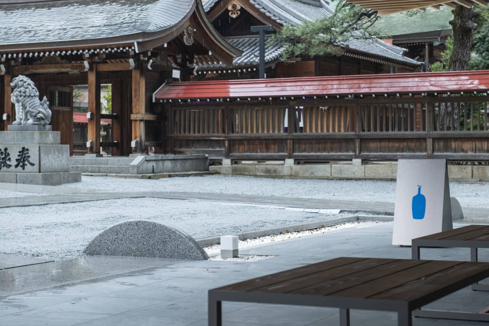 A serene Asian-style courtyard with stone and wood elements, featuring benches and a peaceful atmosphere