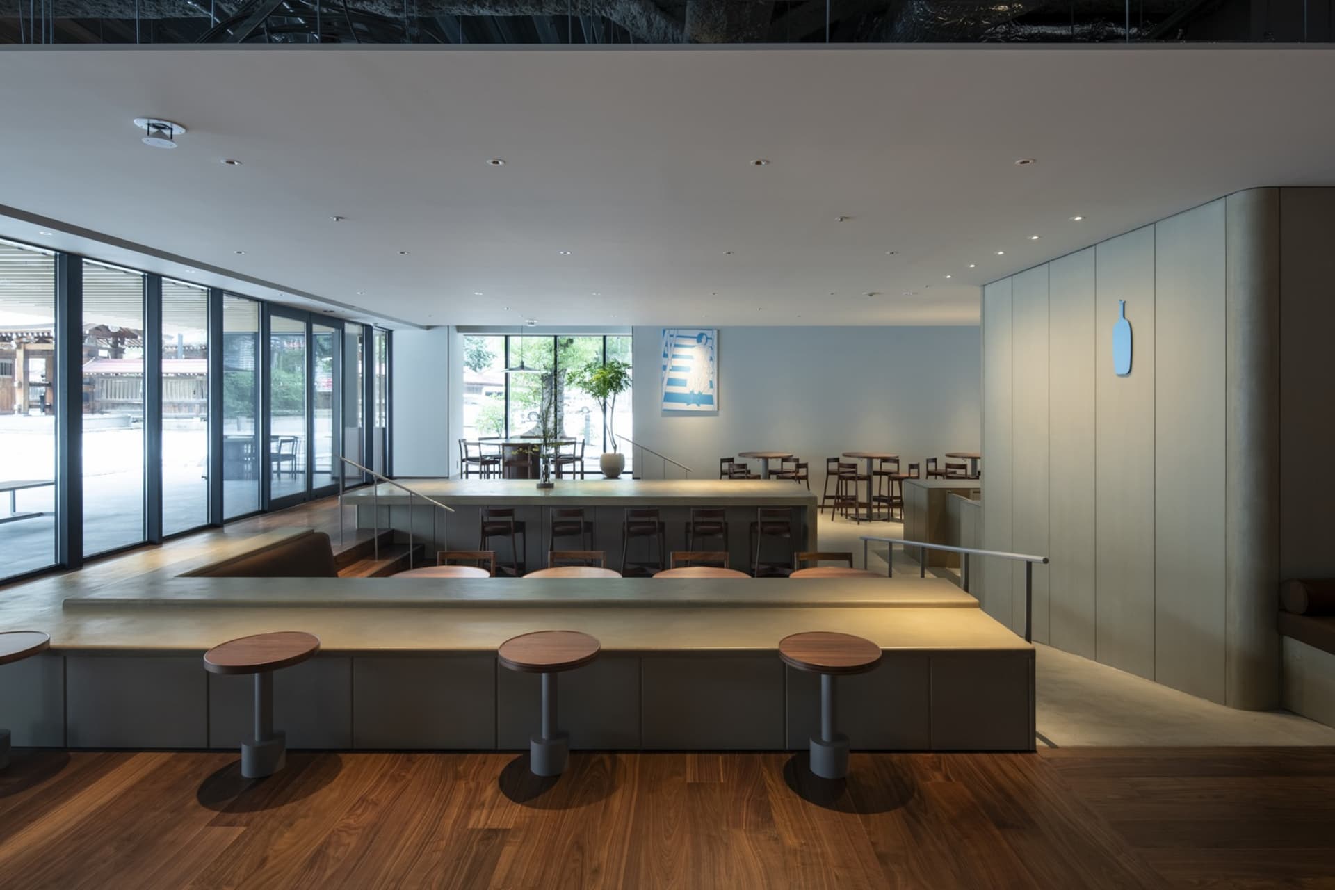 Empty restaurant with wooden floors, tables, and chairs, featuring potted plants and a clean, inviting atmosphere