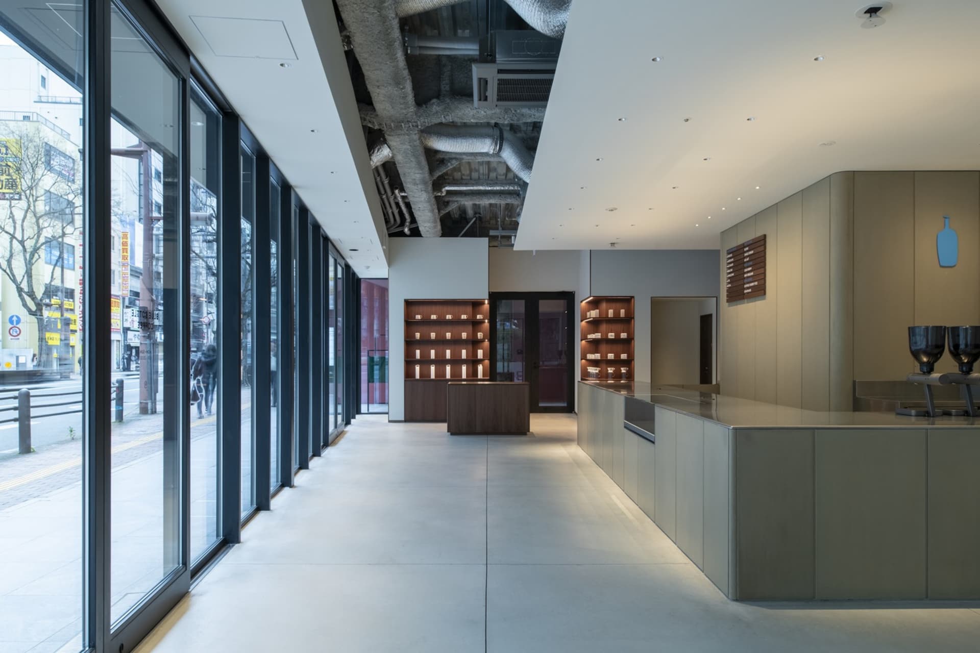 A bright and welcoming lobby with white walls, wooden accents, and natural light from a large window, featuring several people in a modern space
