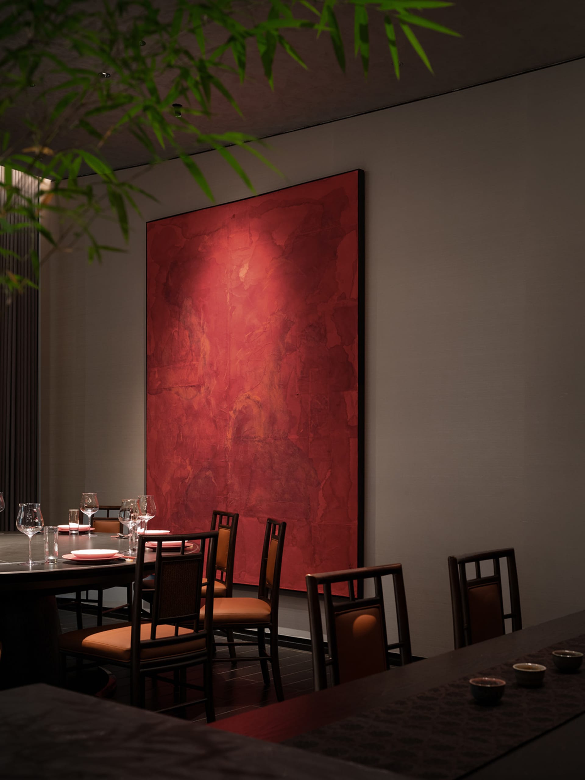 Warm and inviting dining area with a large red painting above a table, surrounded by multiple chairs