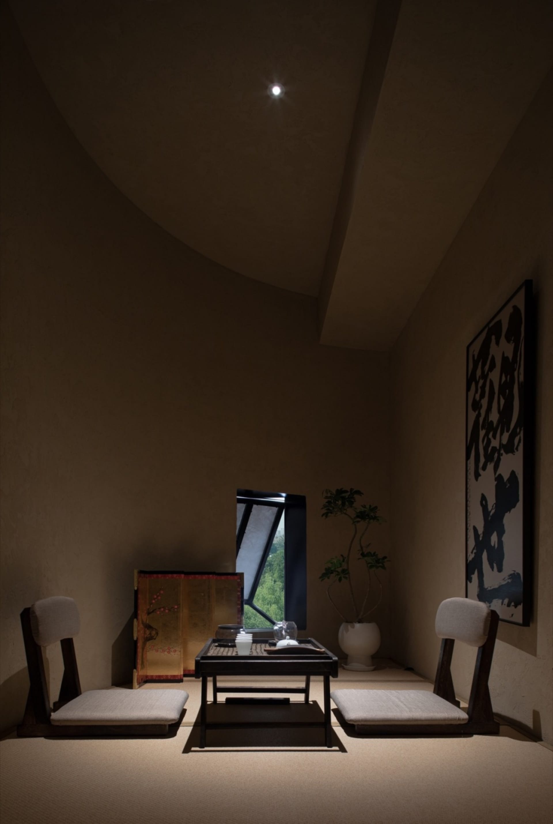 Dimly lit dining room with a table and chairs, adorned with Asian artwork on the walls