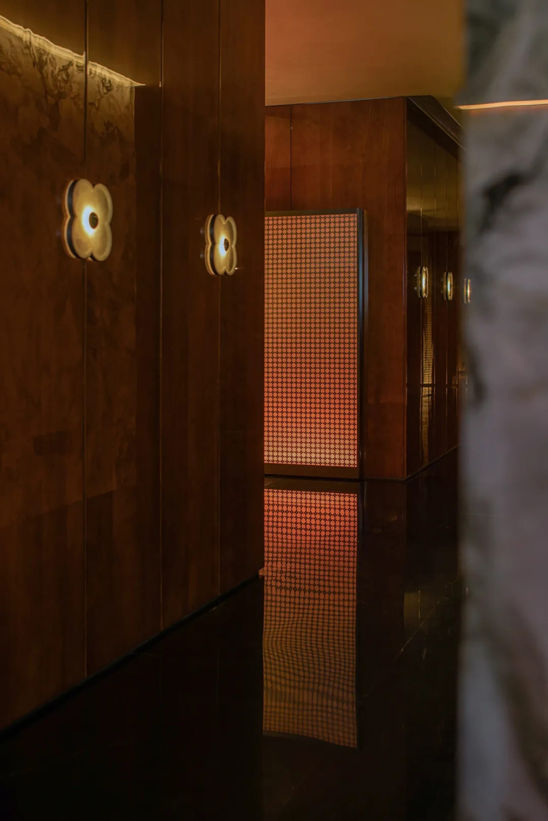 A warm and inviting interior hallway with a wooden floor and walls, lit by two lights on either side