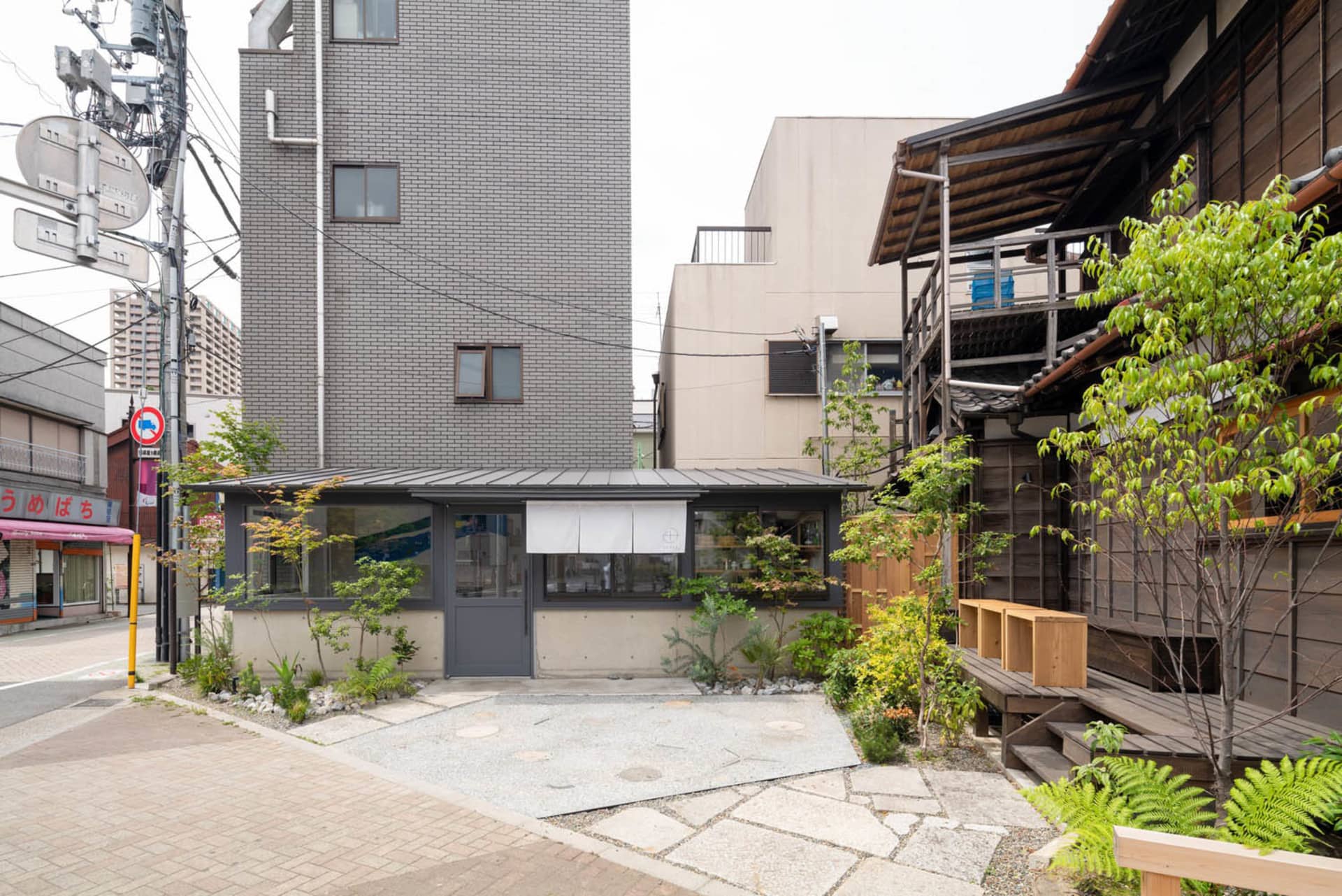 磚牆建築與現代建築相鄰的城市場景，特色為陽台與盆栽植物