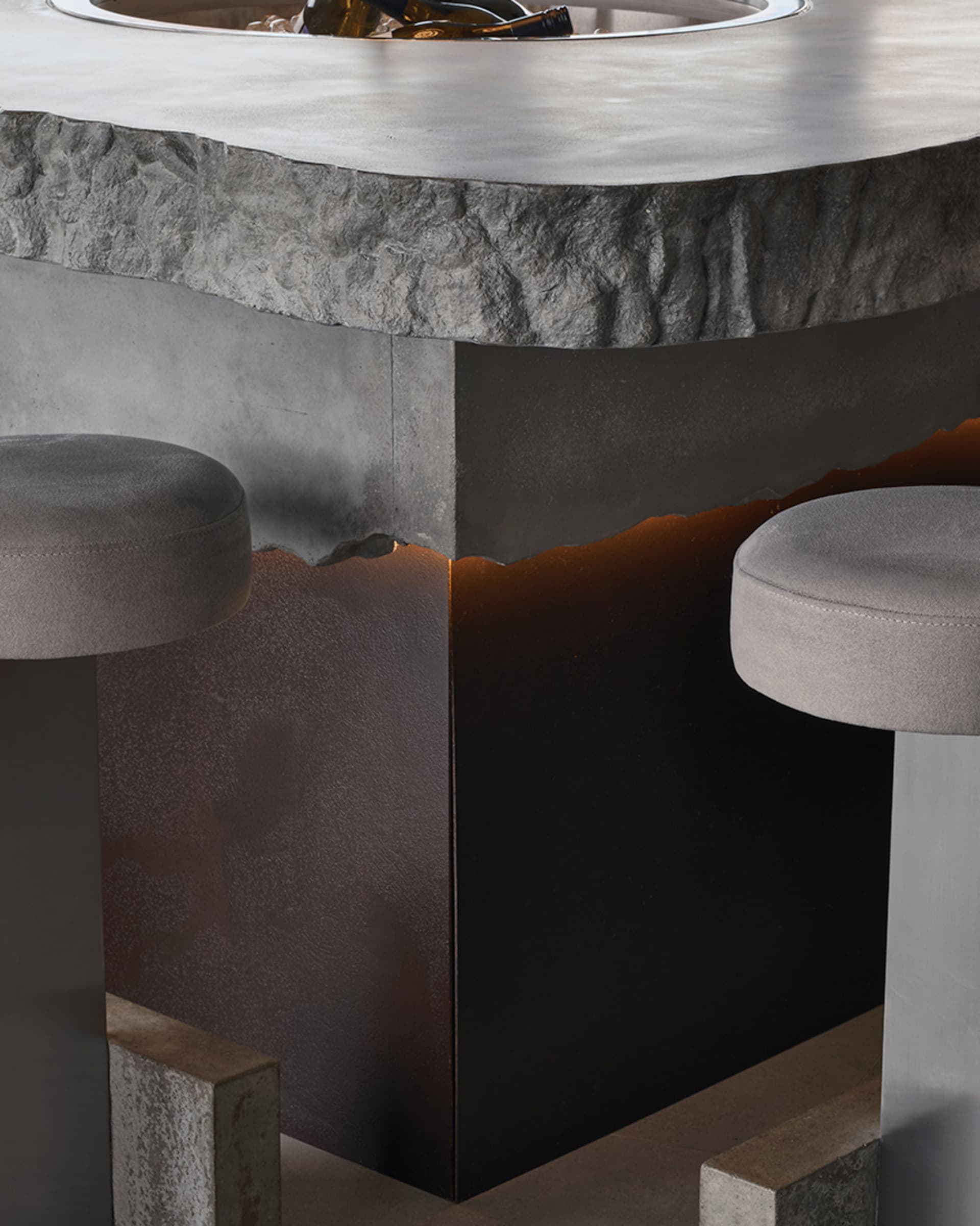 Modern living space with gray stools and a large industrial-style concrete table, set in a contemporary environment