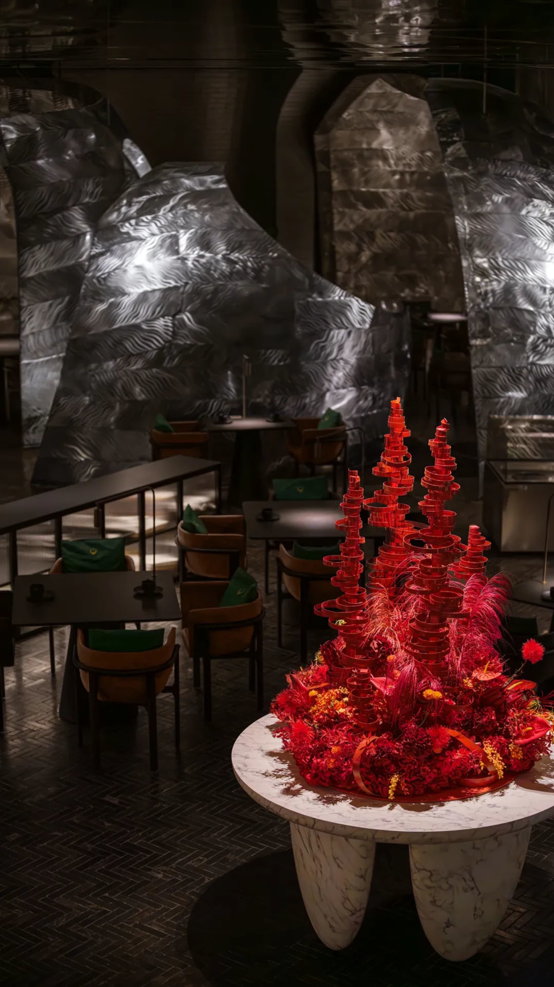 A warm and inviting dining area with a large red tree centerpiece on a table surrounded by chairs, creating a cozy atmosphere in the restaurant
