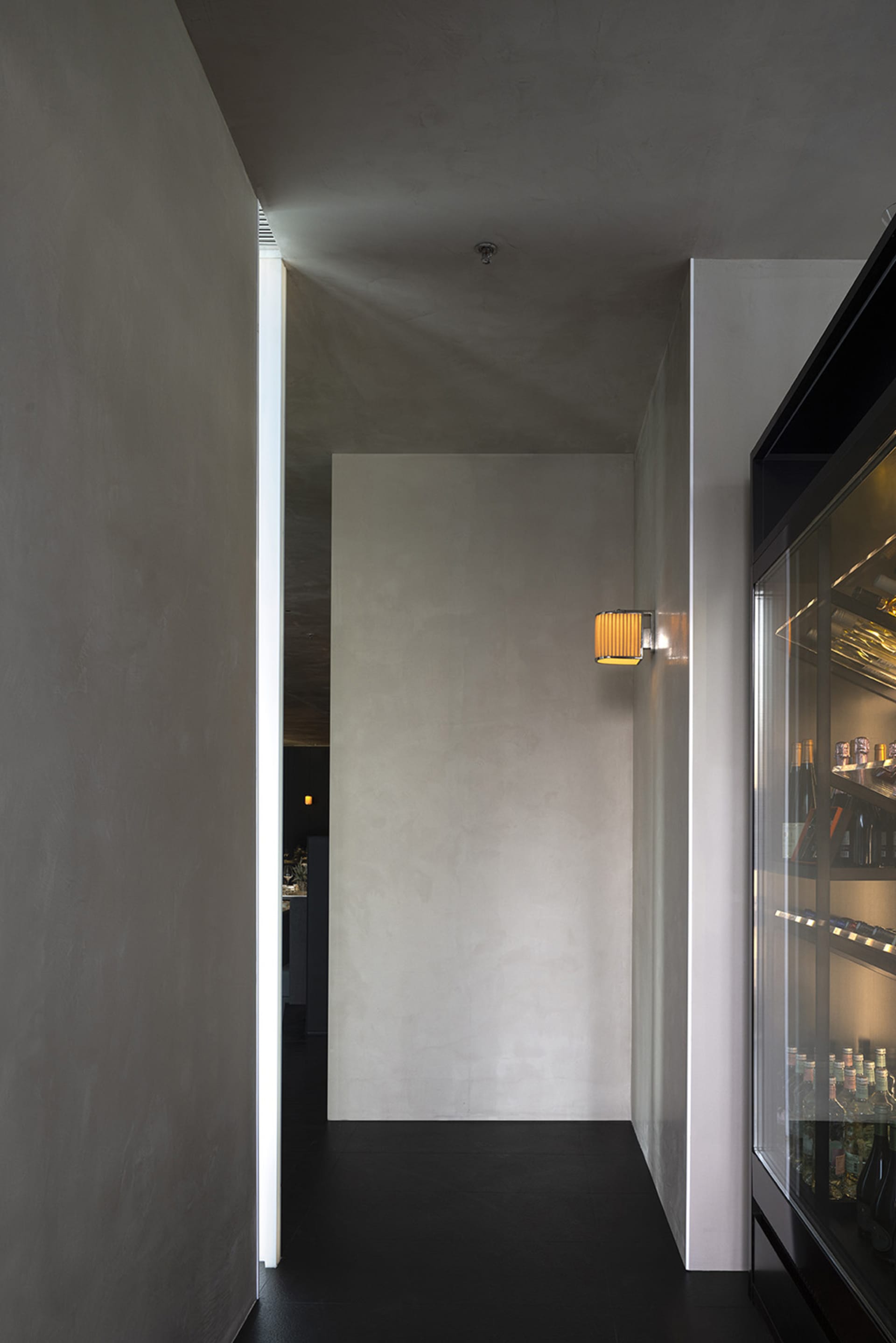 A cozy bar interior with a refrigerator in a corner, surrounded by walls and stocked with various bottles