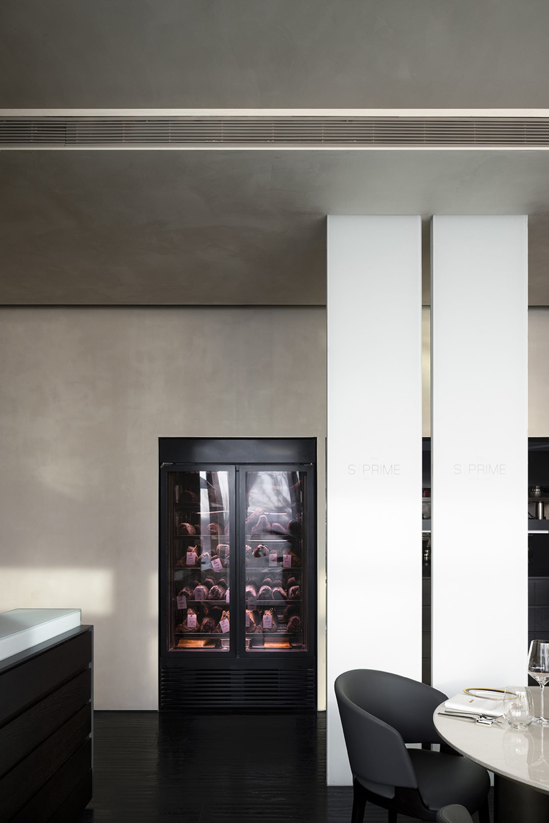 Industrial kitchen with white walls, black appliances, and two large white pillars, exuding a clean and organized atmosphere with a focus on functionality