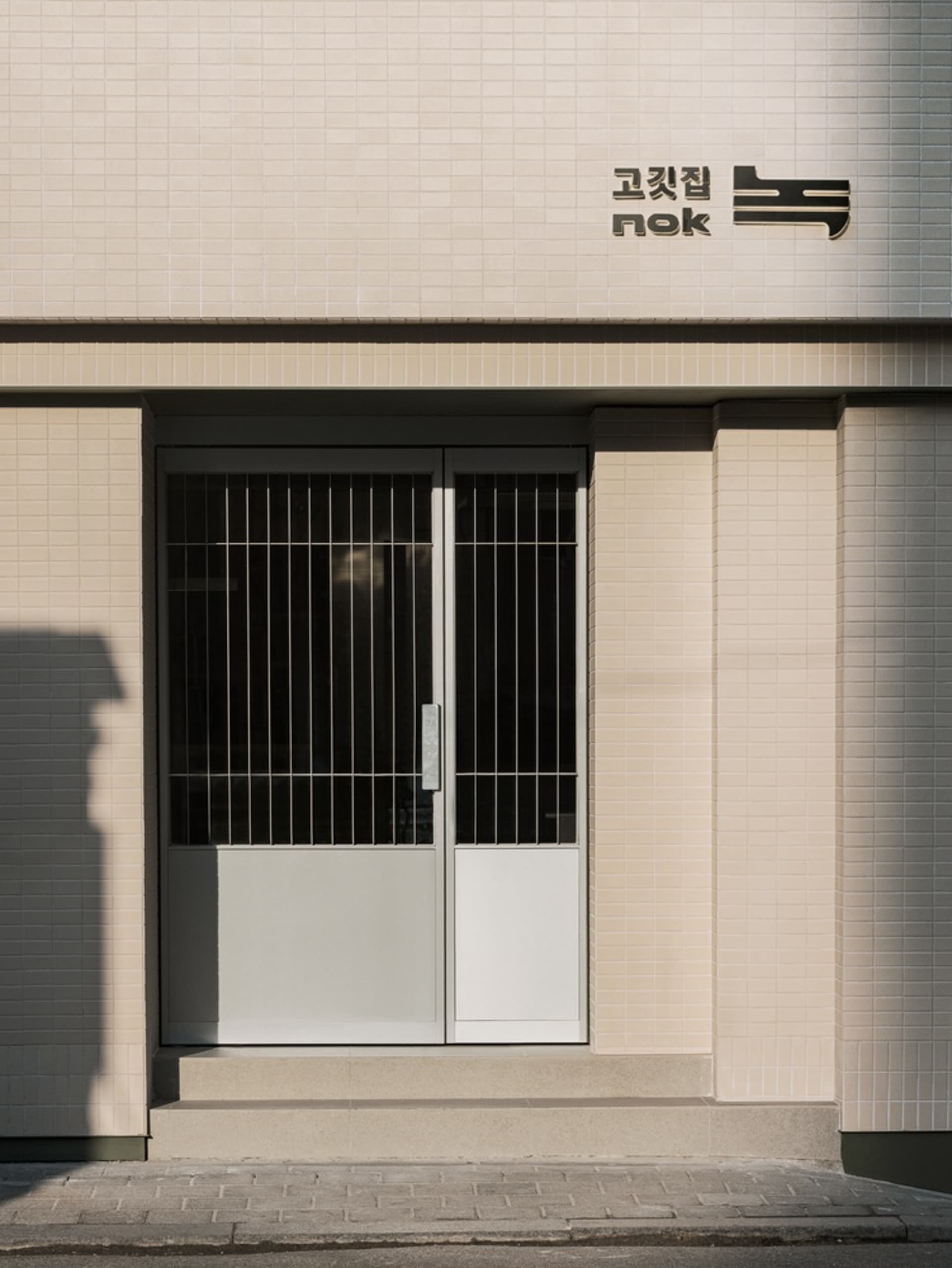 A secure Asian building with a glass door entrance and white brick exterior, conveying a sense of safety and orderliness