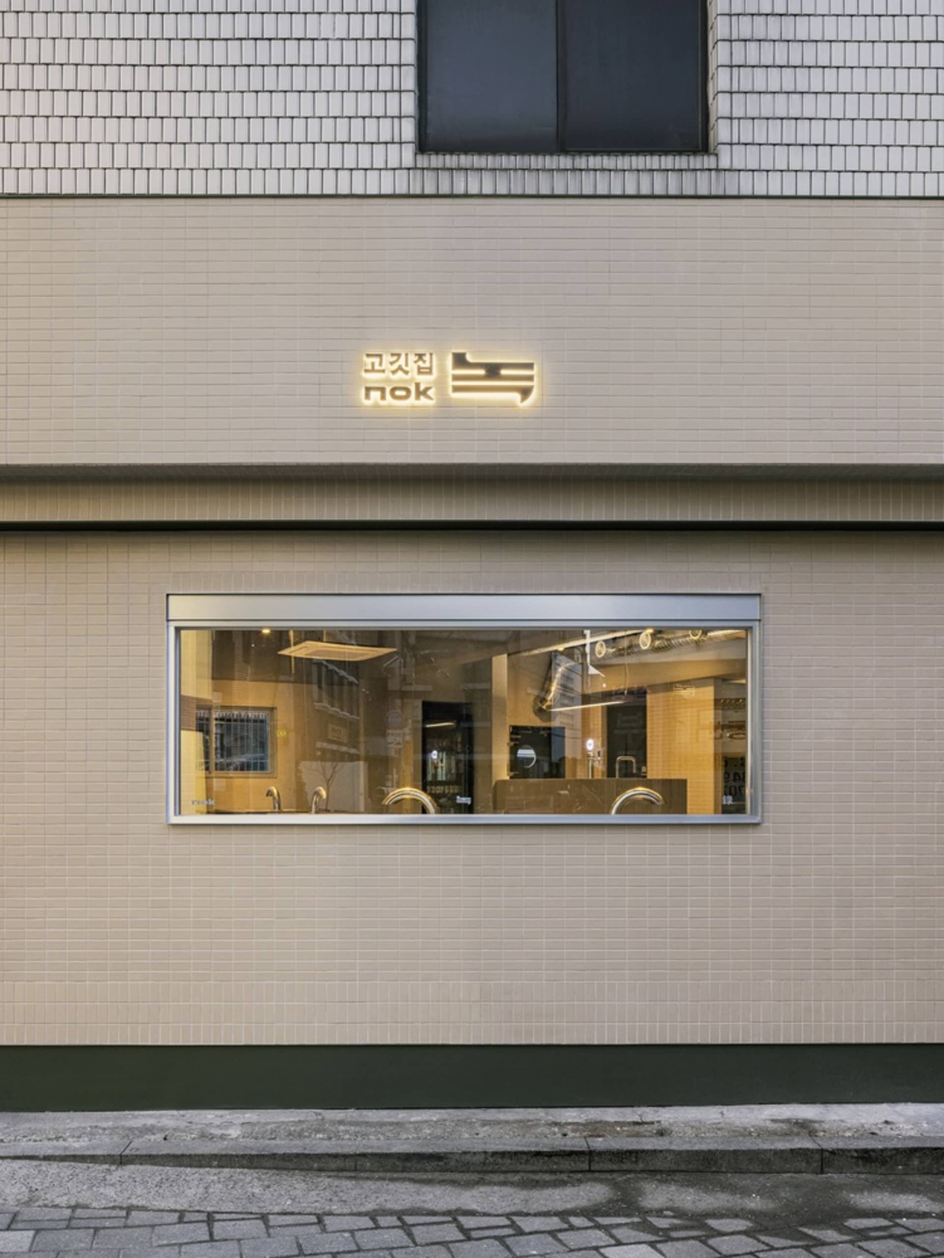 A modern Asian restaurant with a brick exterior, large windows, and comfortable seating areas