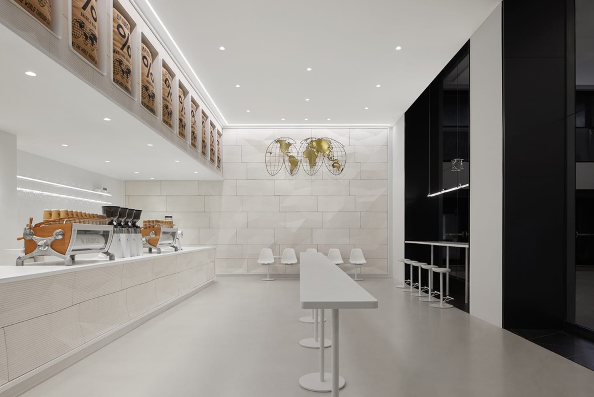 Empty restaurant interior with a large white countertop, chairs, and two dining tables in a clean and well-lit space