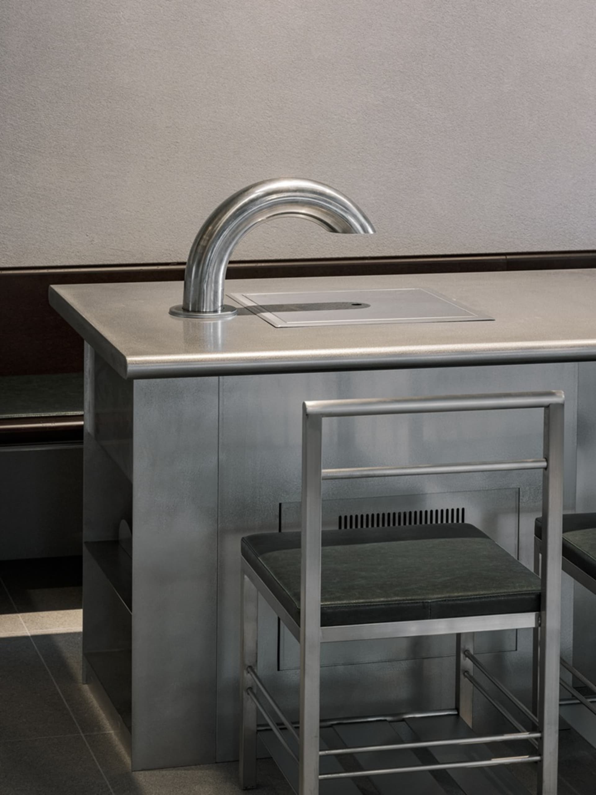 Modern kitchen dining space with a metal sink and wooden dining table, two chairs, and a sleek design