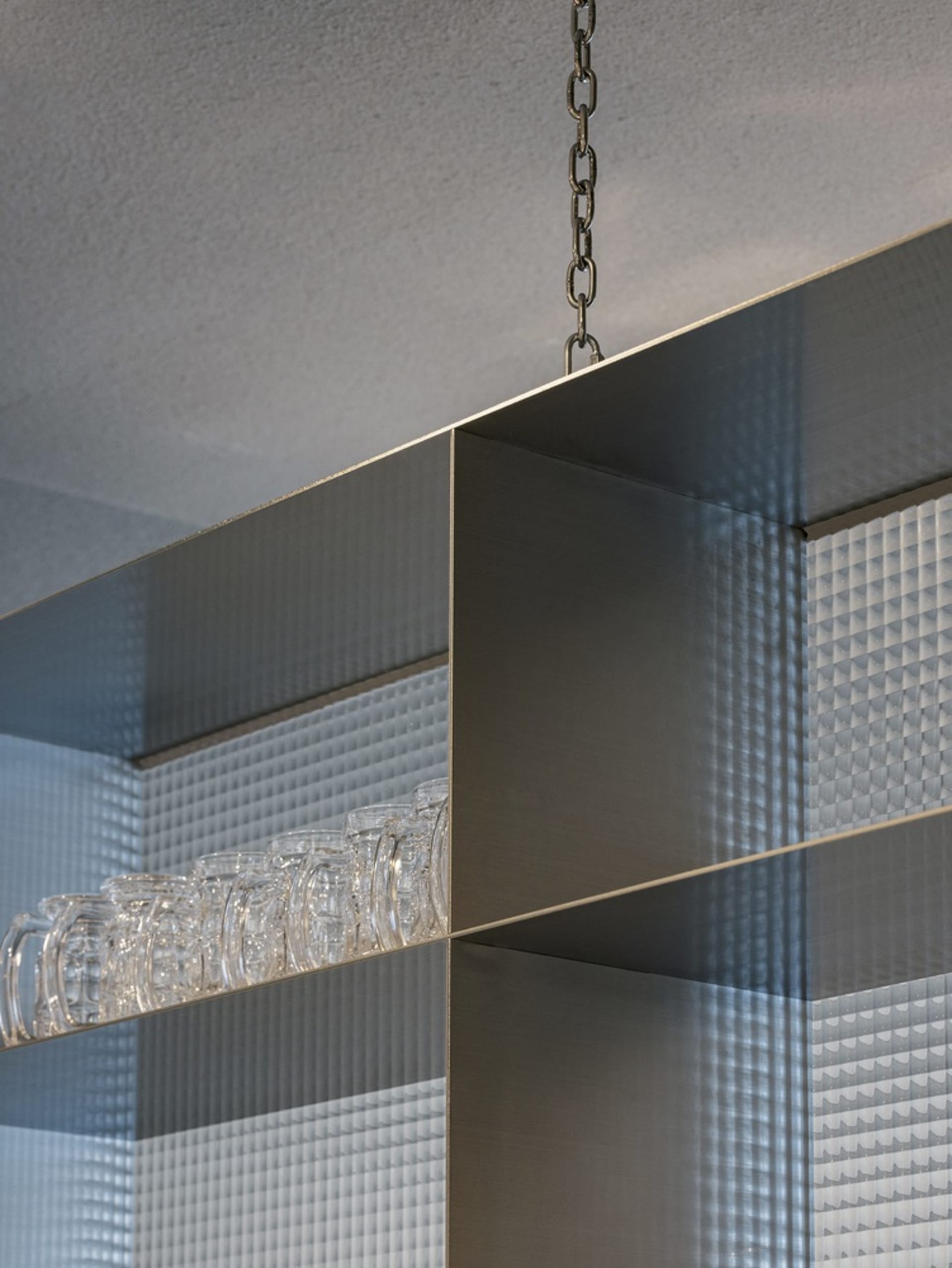 Sleek modern kitchen with industrial metal shelves, wine glasses in various sizes, and a focus on minimalistic design
