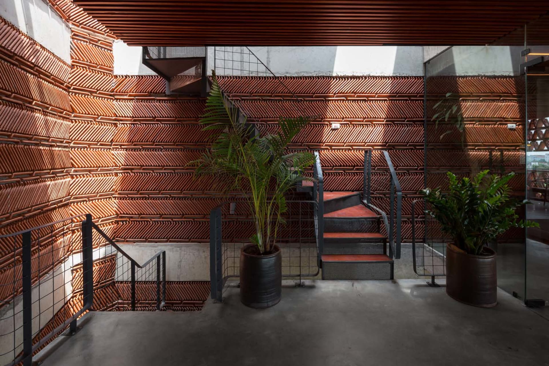 A well-lit stairwell with red steps, two potted plants on either side, and a functional atmosphere