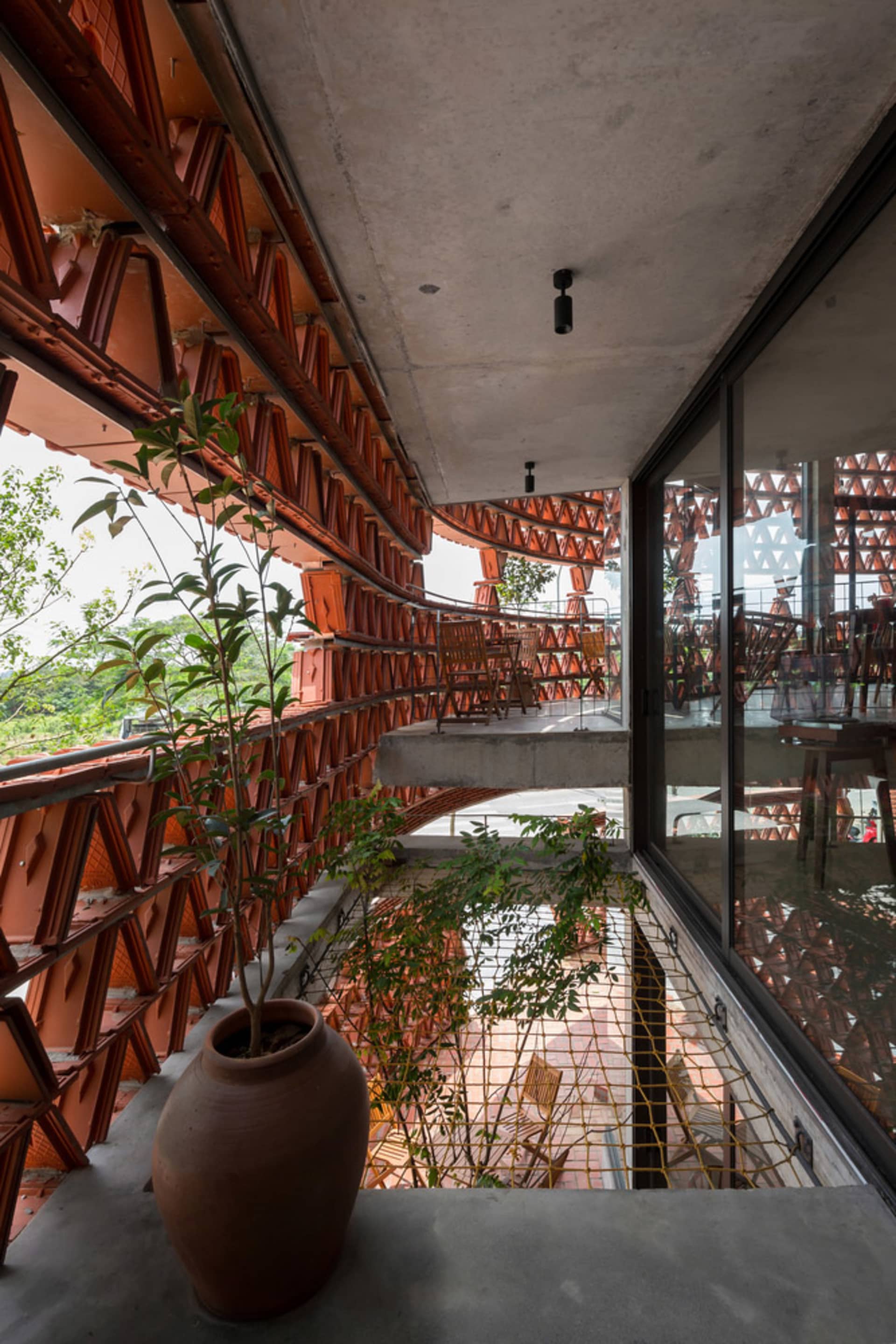 Spacious interior space with red brick walls, a staircase, chairs, and potted plants