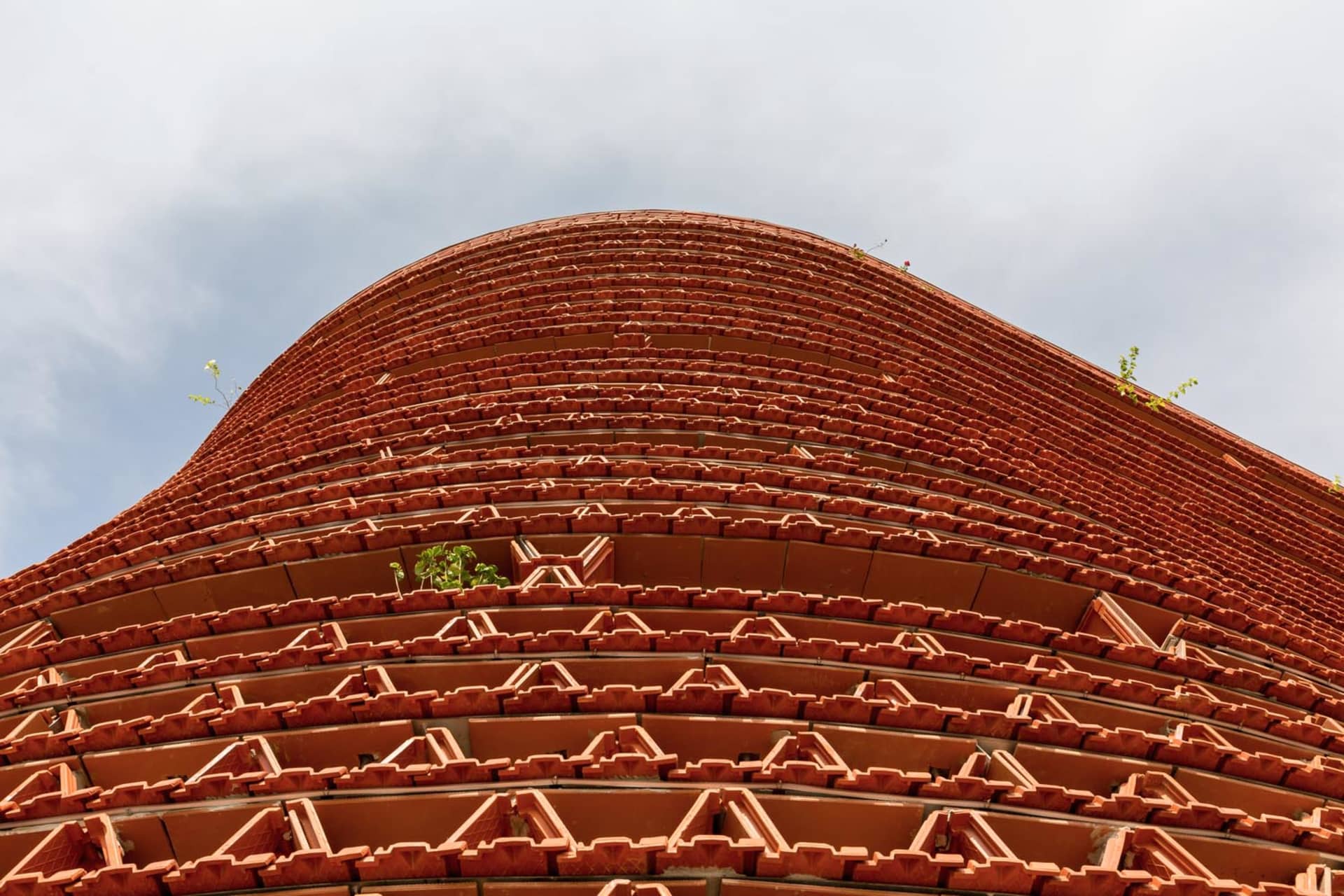 A historic brick building with a red roof and multiple levels, featuring prominent brickwork and a sturdy appearance