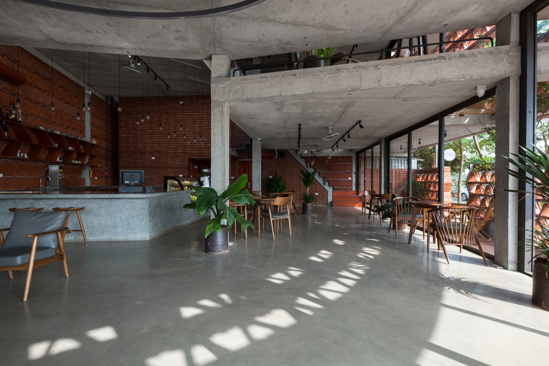 Modern restaurant interior with a large cement wall, concrete floor, and potted plants, featuring a minimalist and functional atmosphere