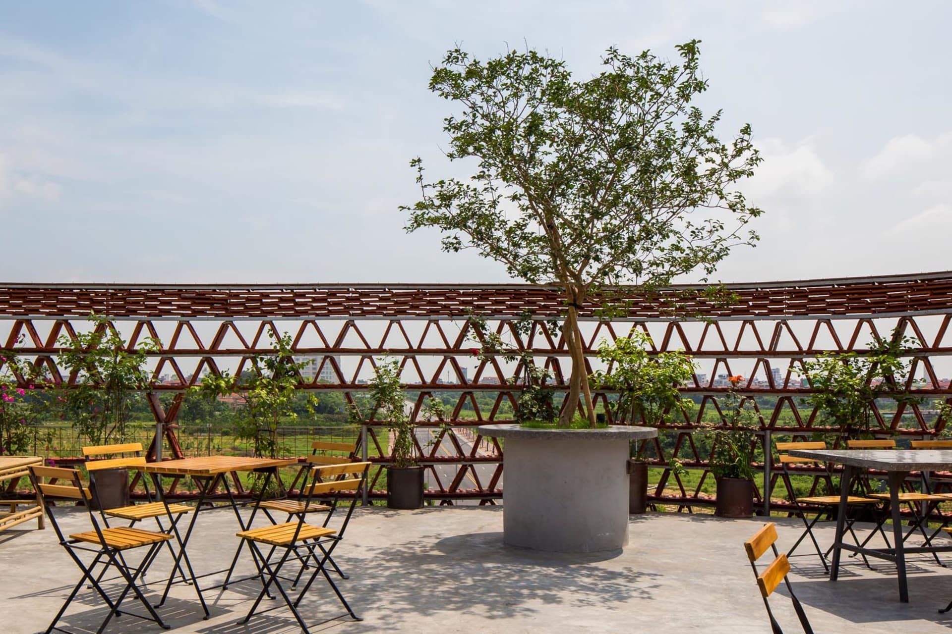 A relaxed outdoor patio area with stone tables, umbrellas, and potted plants, perfect for dining or conversation