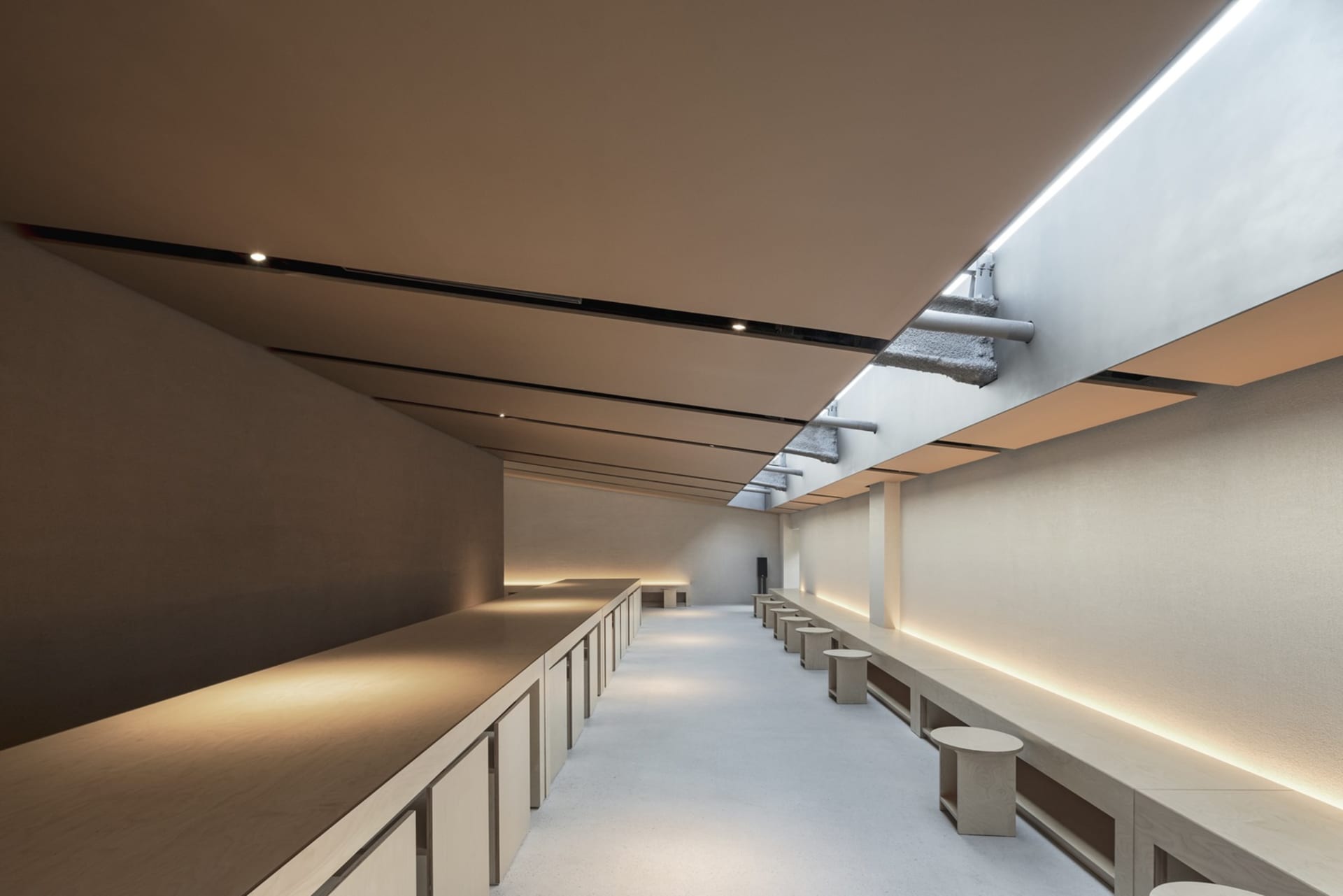 Empty modern room with a long countertop and benches, well-lit and minimalist in design