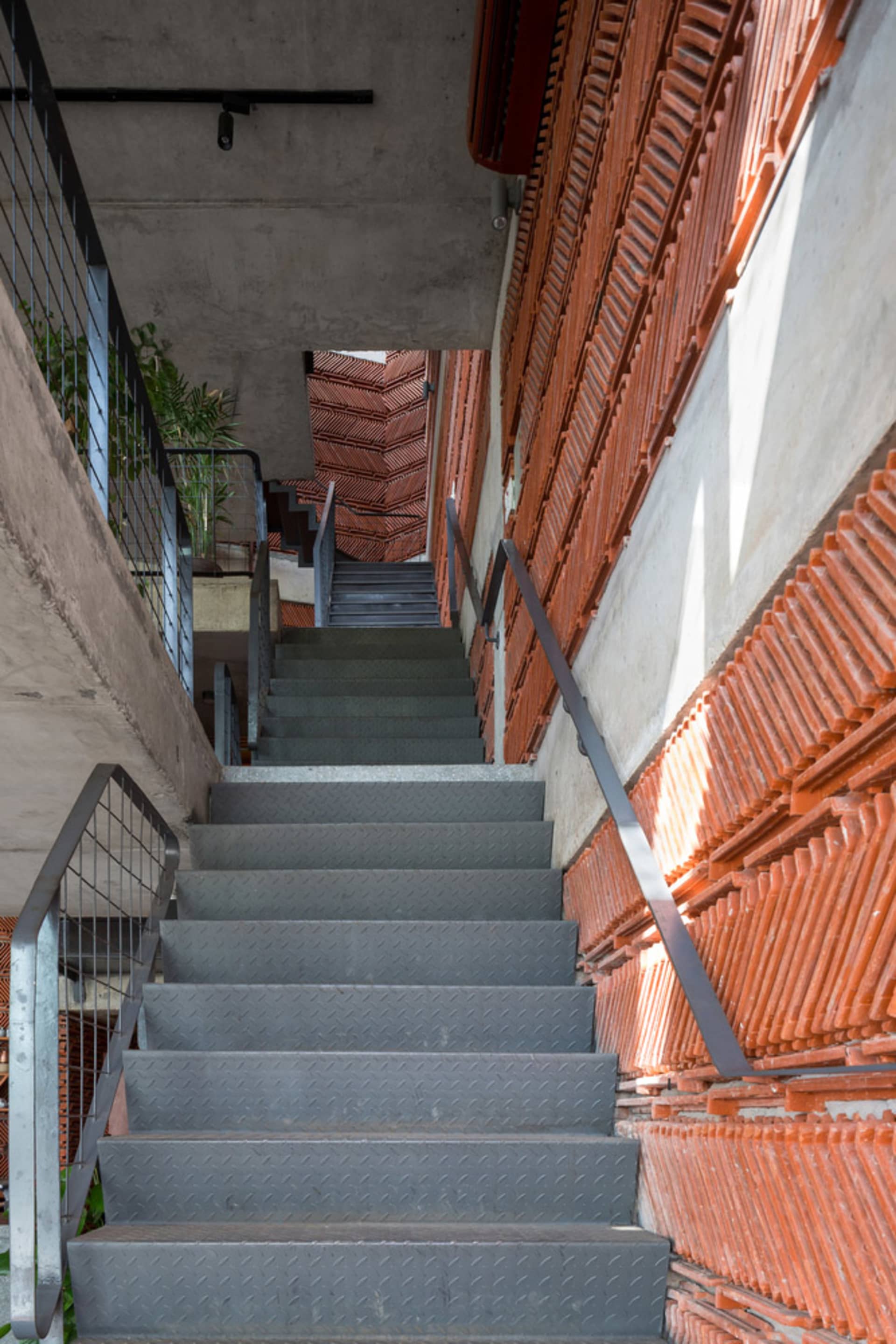 A modern building with multiple levels, stairs, and neutral tones, featuring concrete and metal construction, with natural light and a calm atmosphere