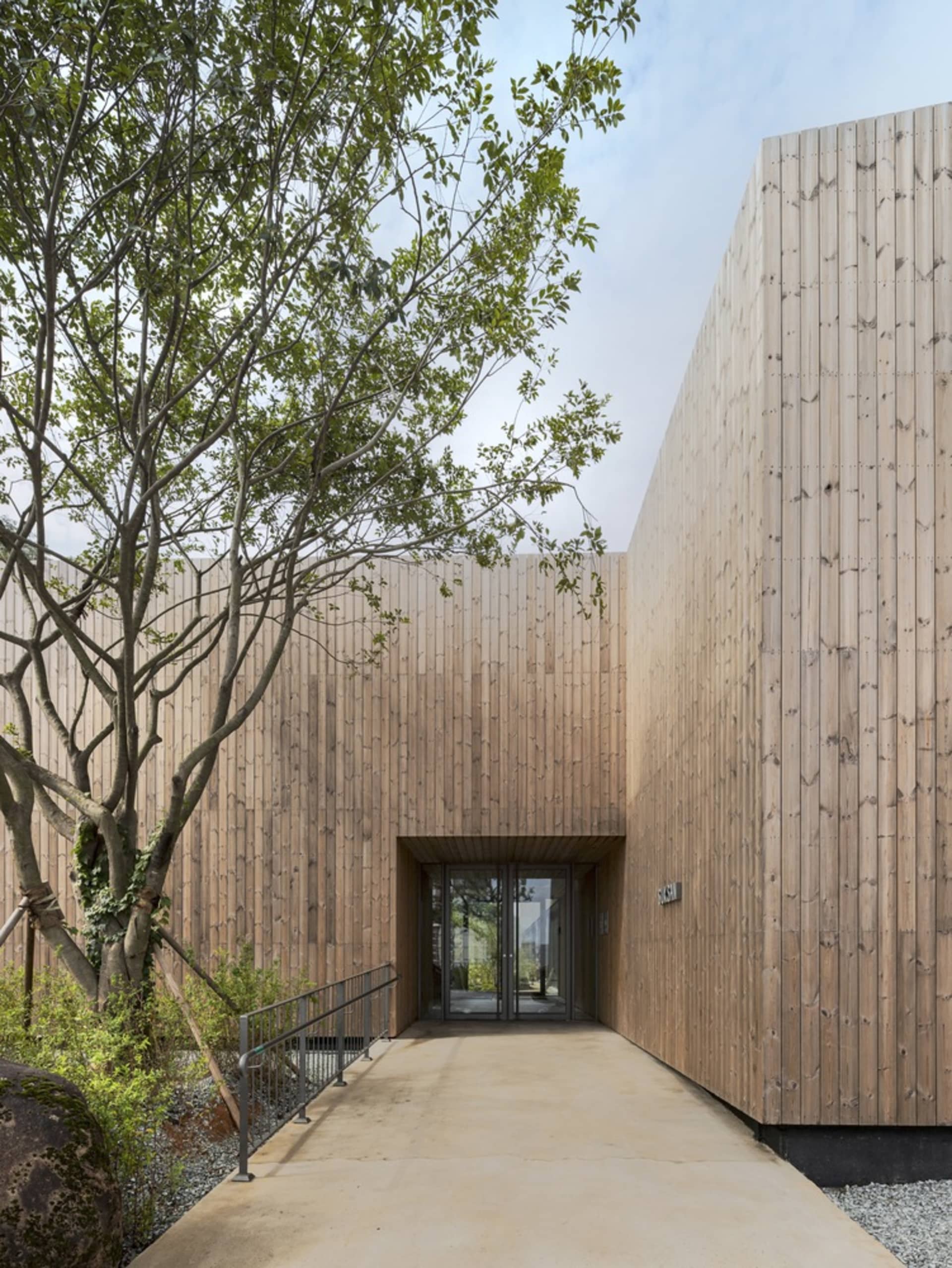 A building with wooden walls and a glass door, featuring a large window for natural light and a warm, inviting atmosphere
