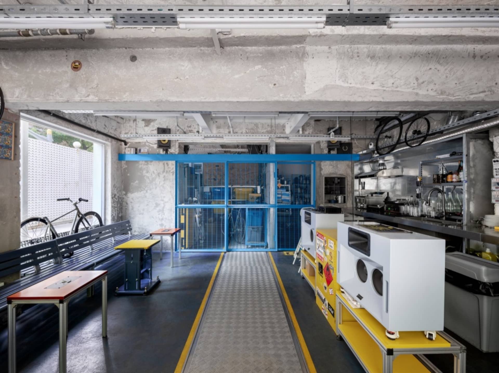 Industrial open space with a yellow walkway, benches, and bicycles, showcasing the interior design and layout of the building