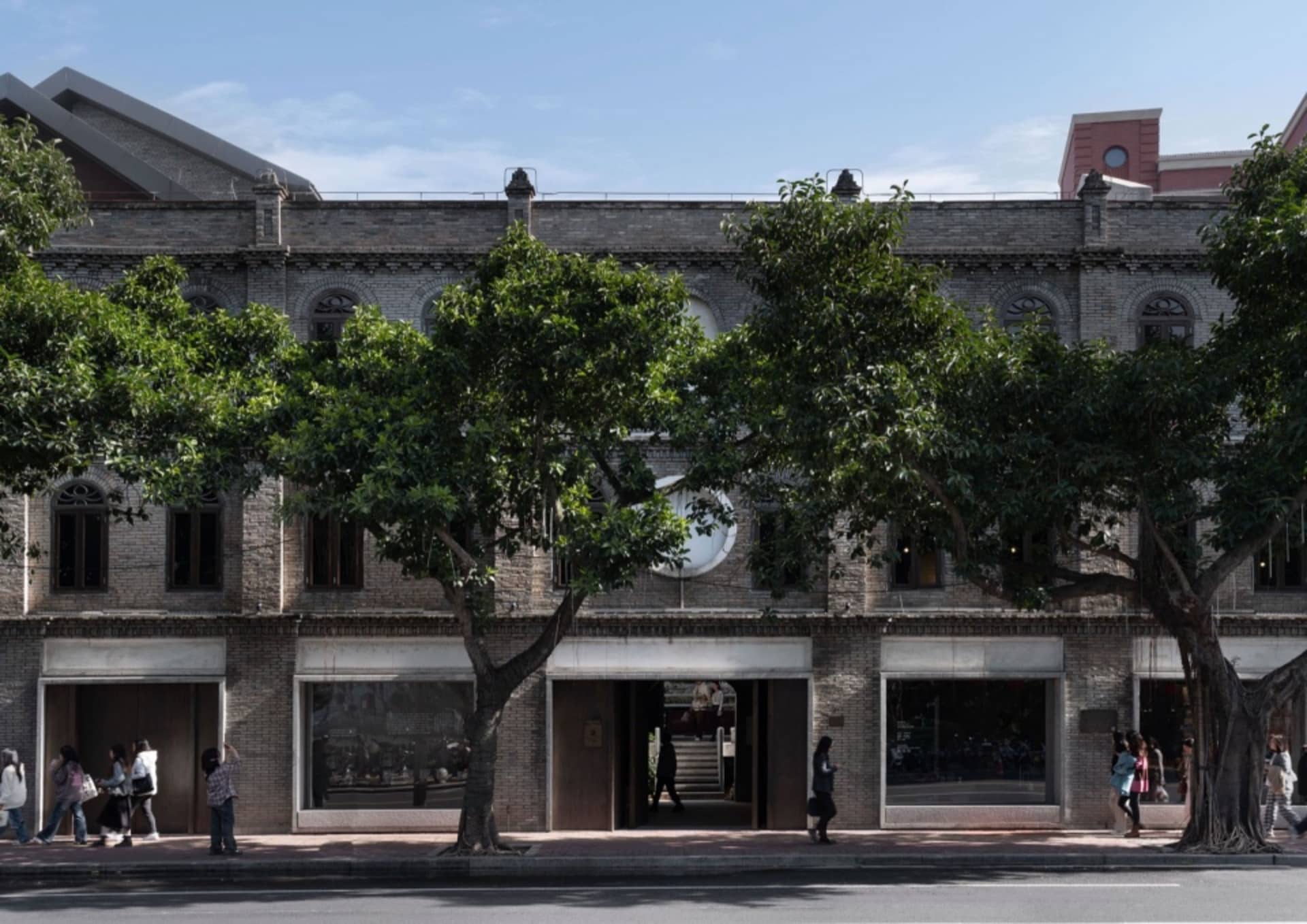 A classic brick building with a tree in front, providing shade and a touch of nature to the urban environment