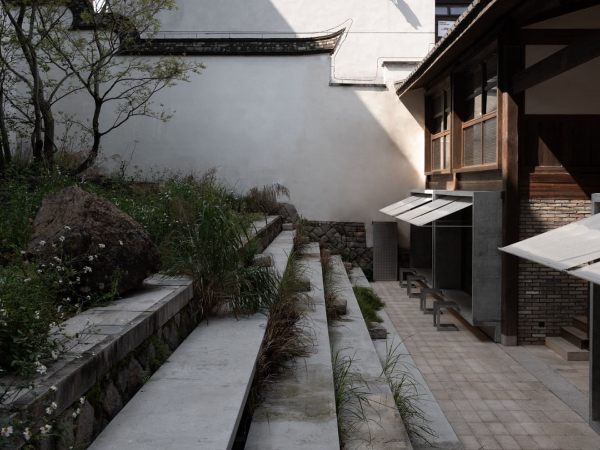 A serene building with a stone exterior, two wooden benches, and a peaceful atmosphere