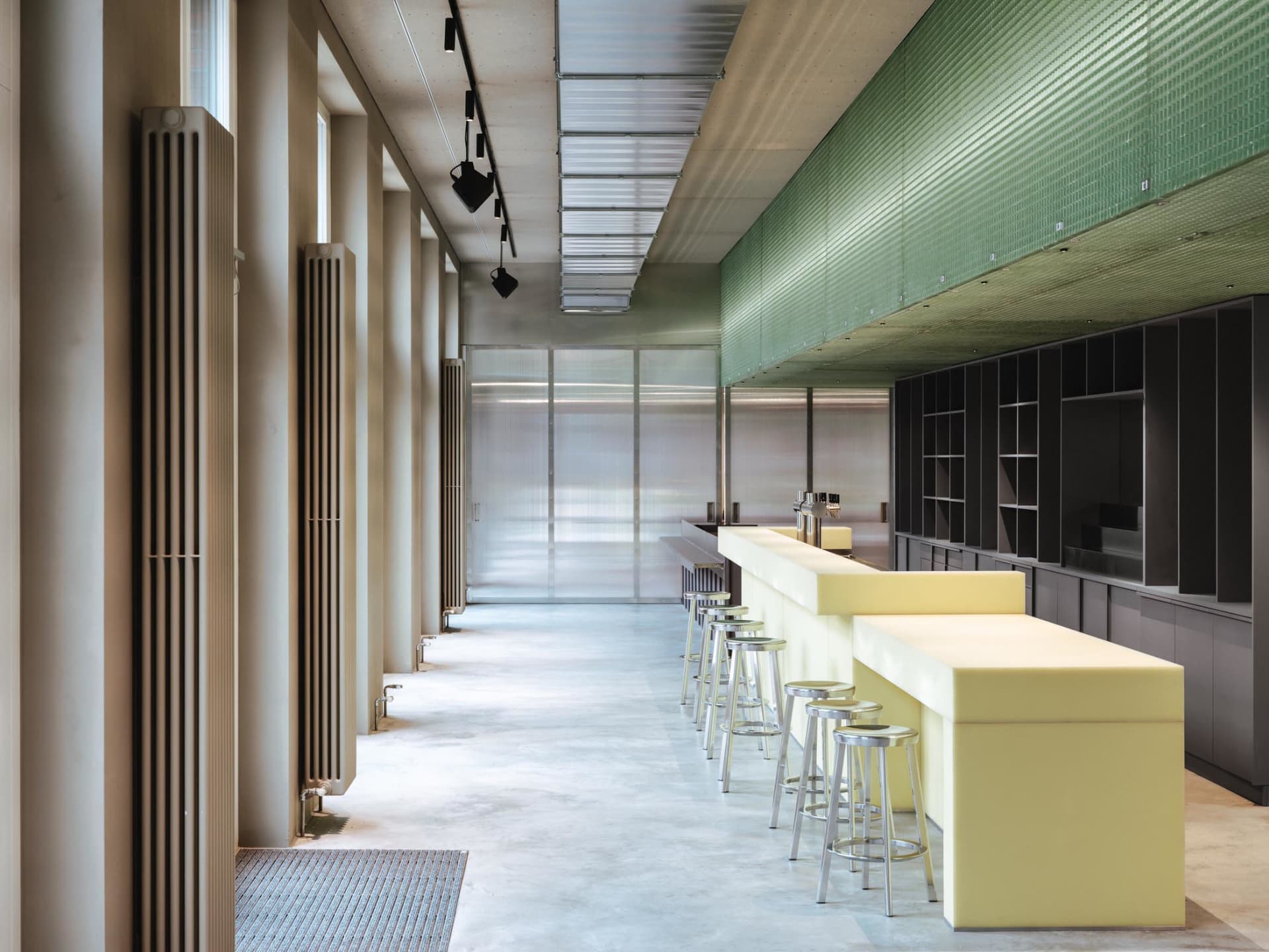 Modern restaurant interior with a long bar counter, stools, chairs, and warm lighting