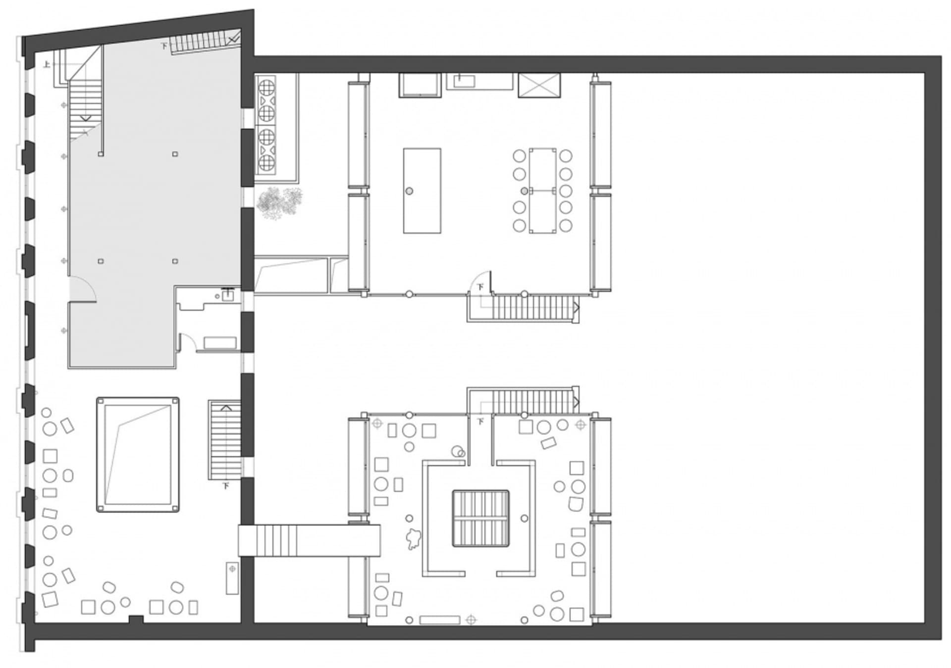A dimly lit interior space with a mix of rooms, including a dining area and living room, featuring concrete walls, hardwood flooring, and cozy lighting