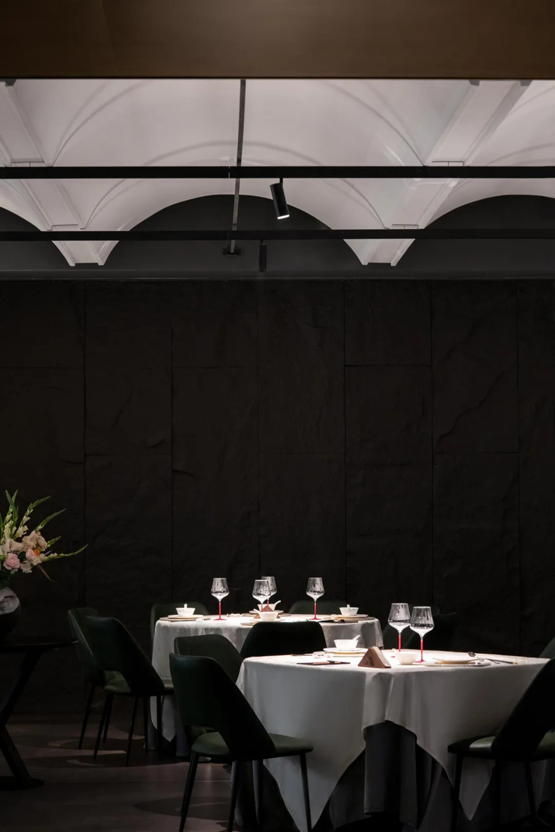 Elegant dining area with a black table, green chairs, wine glasses, cups, and bowls, set for a formal dinner