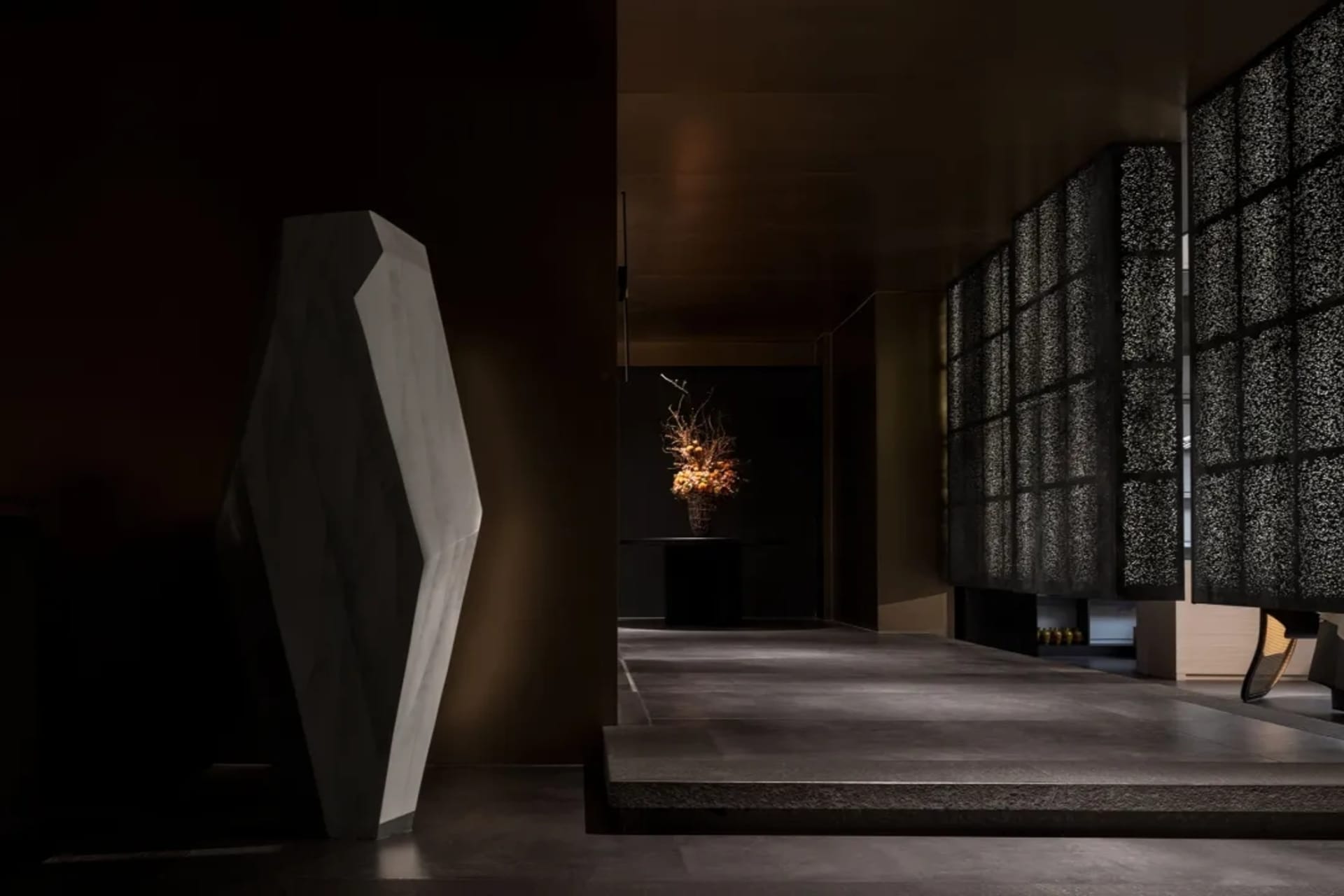 Elegant hallway with a stone wall, marble floor, vases, and a potted plant, creating a sophisticated atmosphere