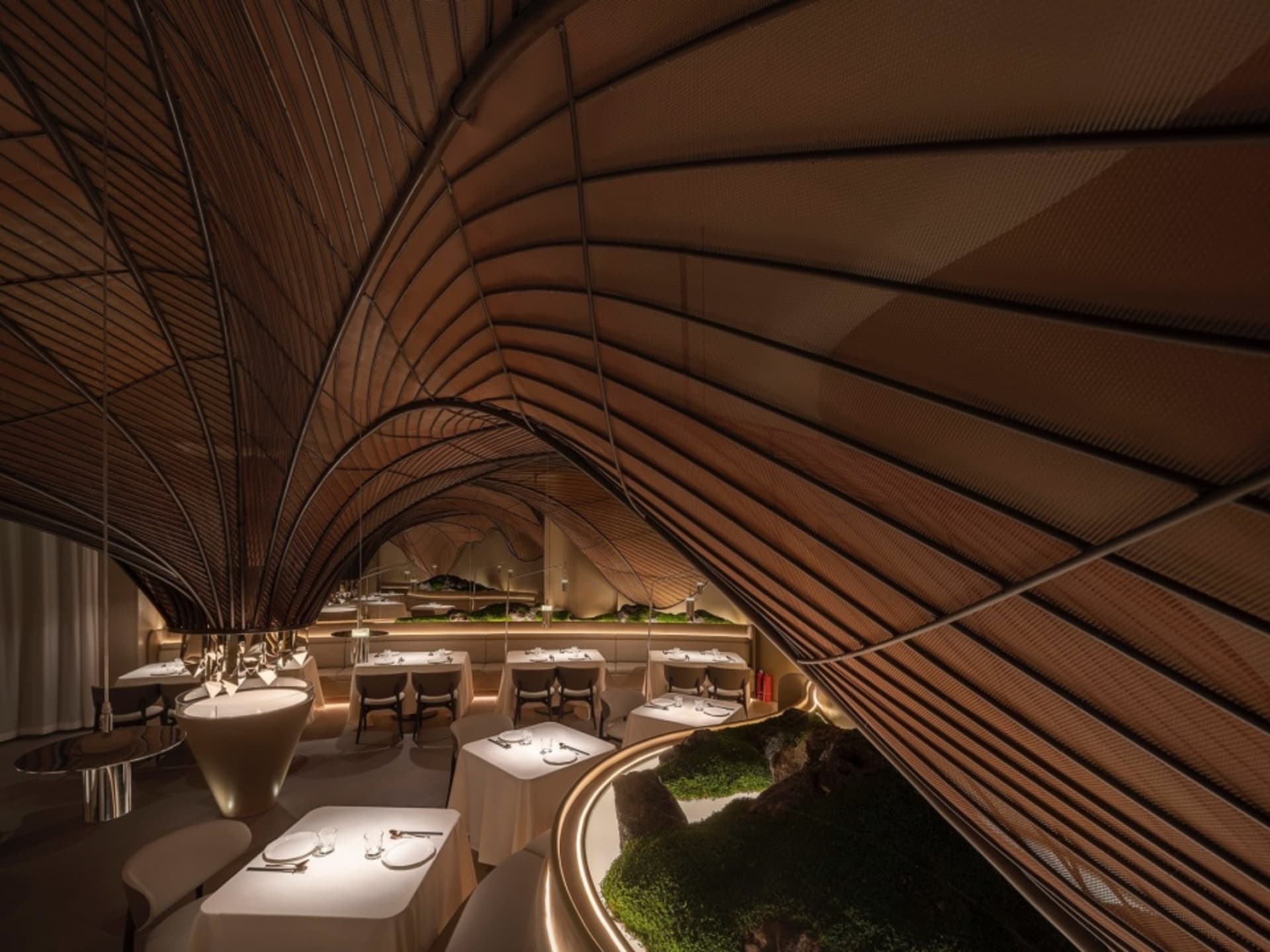 A modern restaurant dining area with a curved ceiling, wooden elements, and comfortable seating, featuring ample tables and chairs in a sophisticated setting