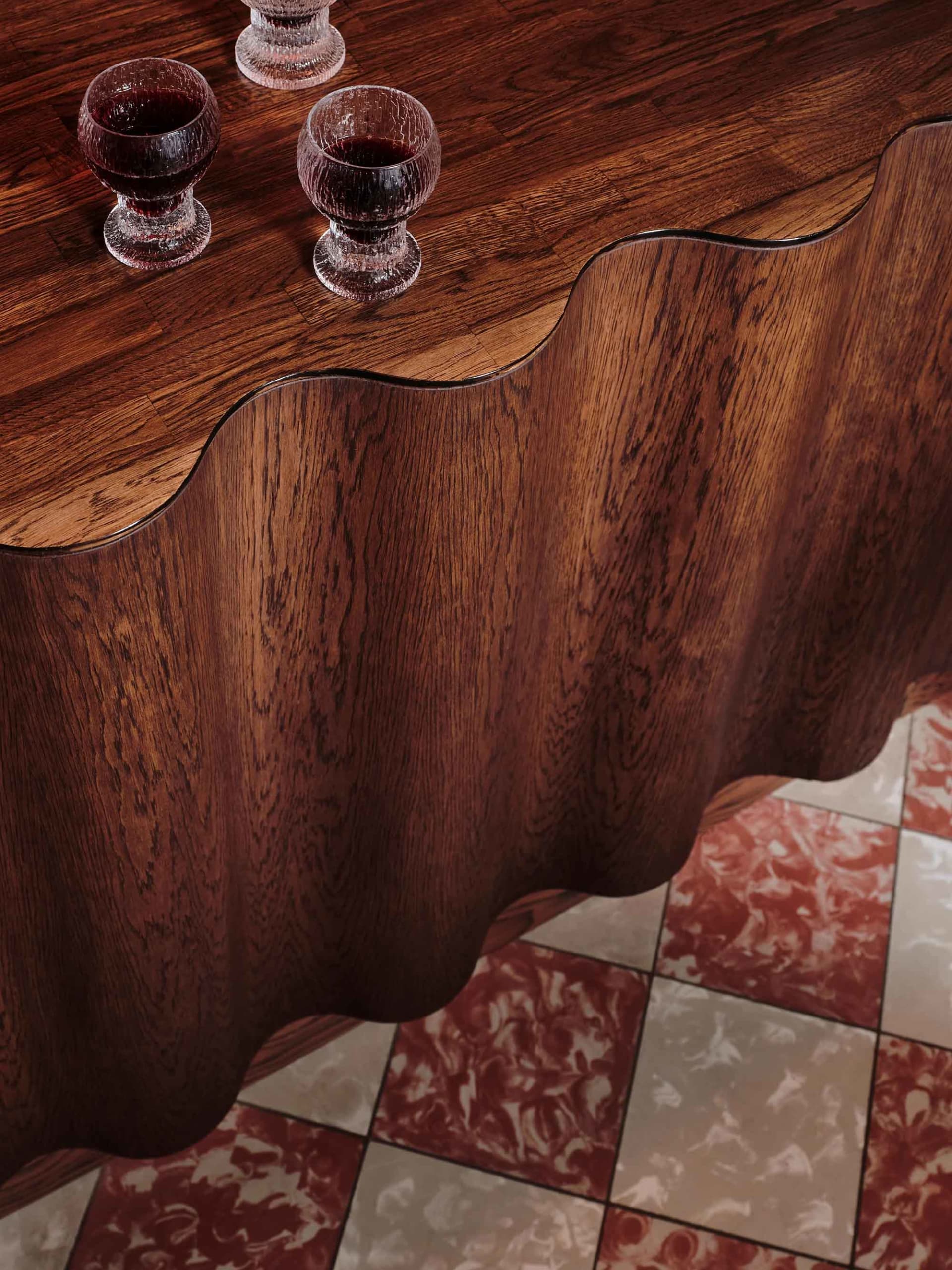 A wooden table with two wine glasses and red liquid, creating a relaxed and sophisticated atmosphere