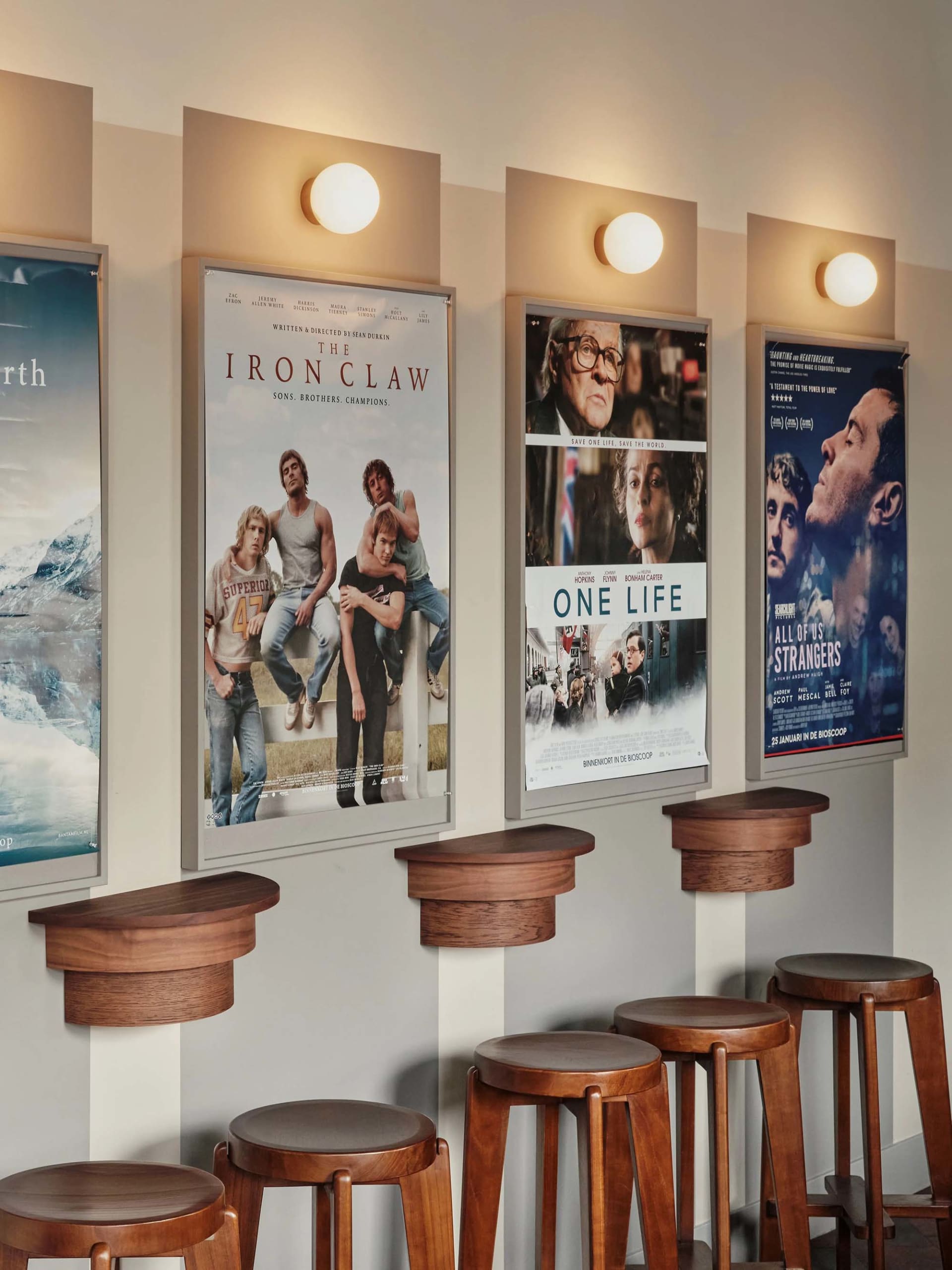 A casual space with a row of wooden stools against a wall, accompanied by three posters on the wall above, creating a welcoming atmosphere
