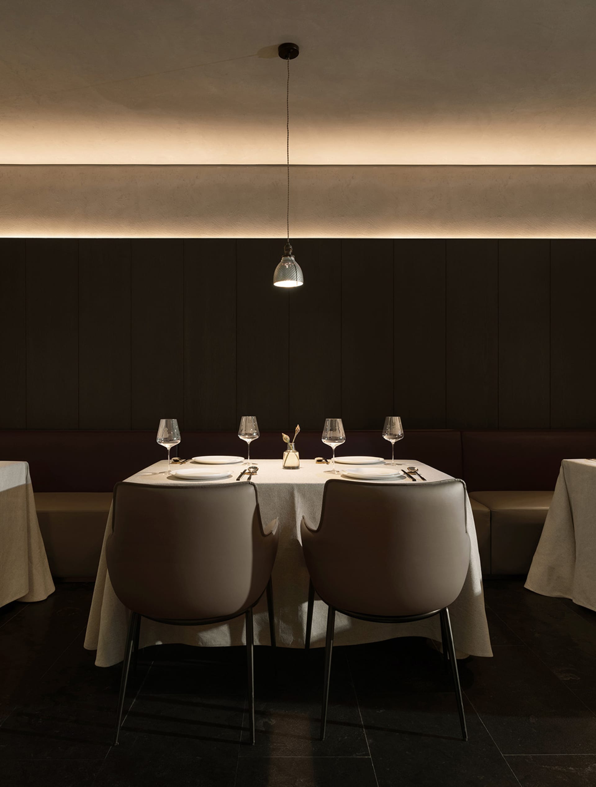 A formal dining area with a large table and chairs, wine glasses, and neatly arranged utensils, set in a sophisticated and inviting atmosphere